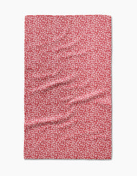 A Flower Seeds tea towel by Amita Nair, made of Geoweave fabric in red with a pattern of small white leaf-like shapes, shown laid flat with slight surface wrinkles.
