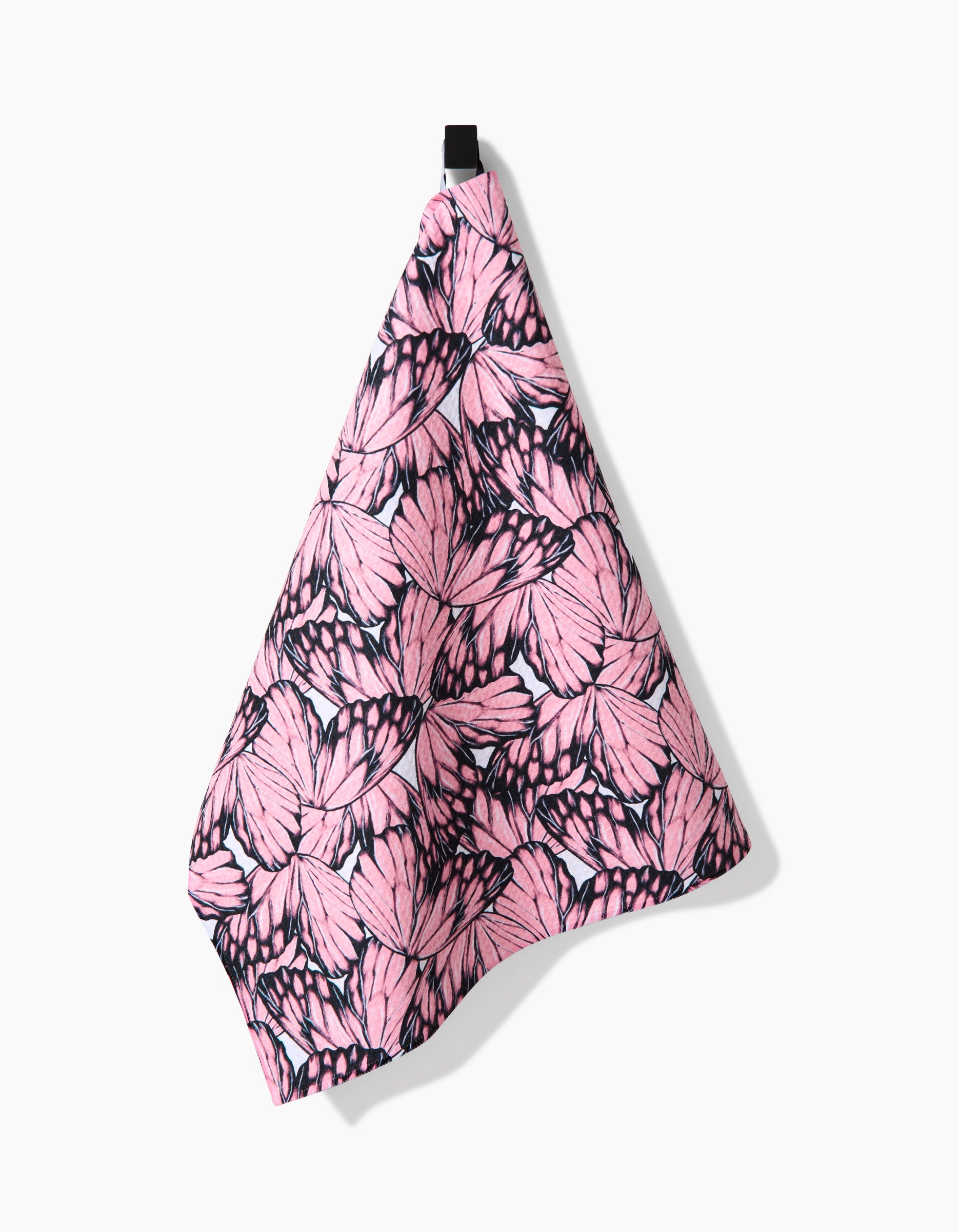 The Aubrey Fairchild Flutter by Butterfly is a hanging pink tea towel with a black loop, showcasing black-outlined butterfly wings on Geoweave™ fabric made from recycled materials.
