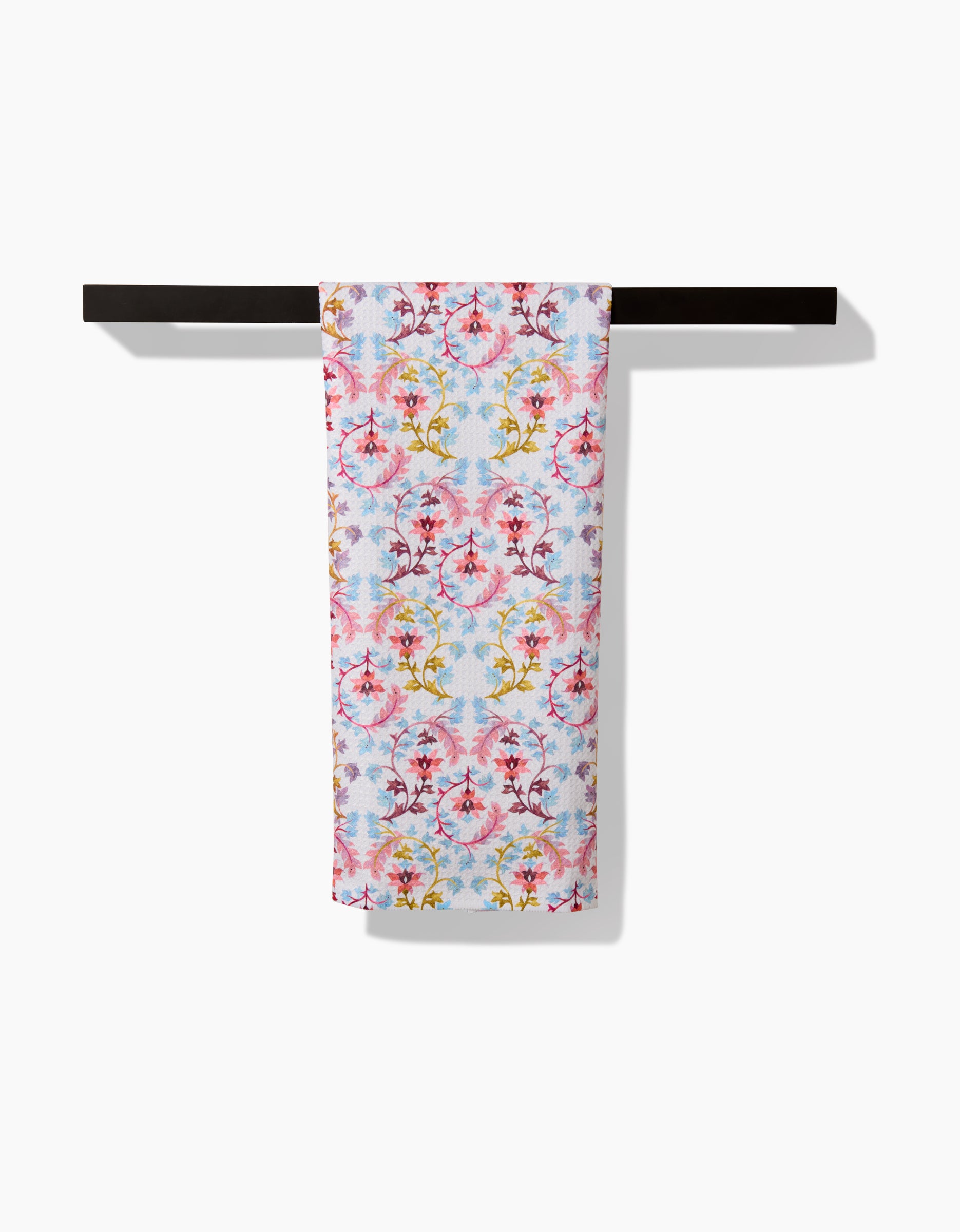 The Folk Tapestry towel by Maayan Alper-Swan features a vibrant floral design in pink, yellow, and red on light blue ultra-absorbent Geoweave fabric, shown neatly folded on a black towel bar against a plain white background.