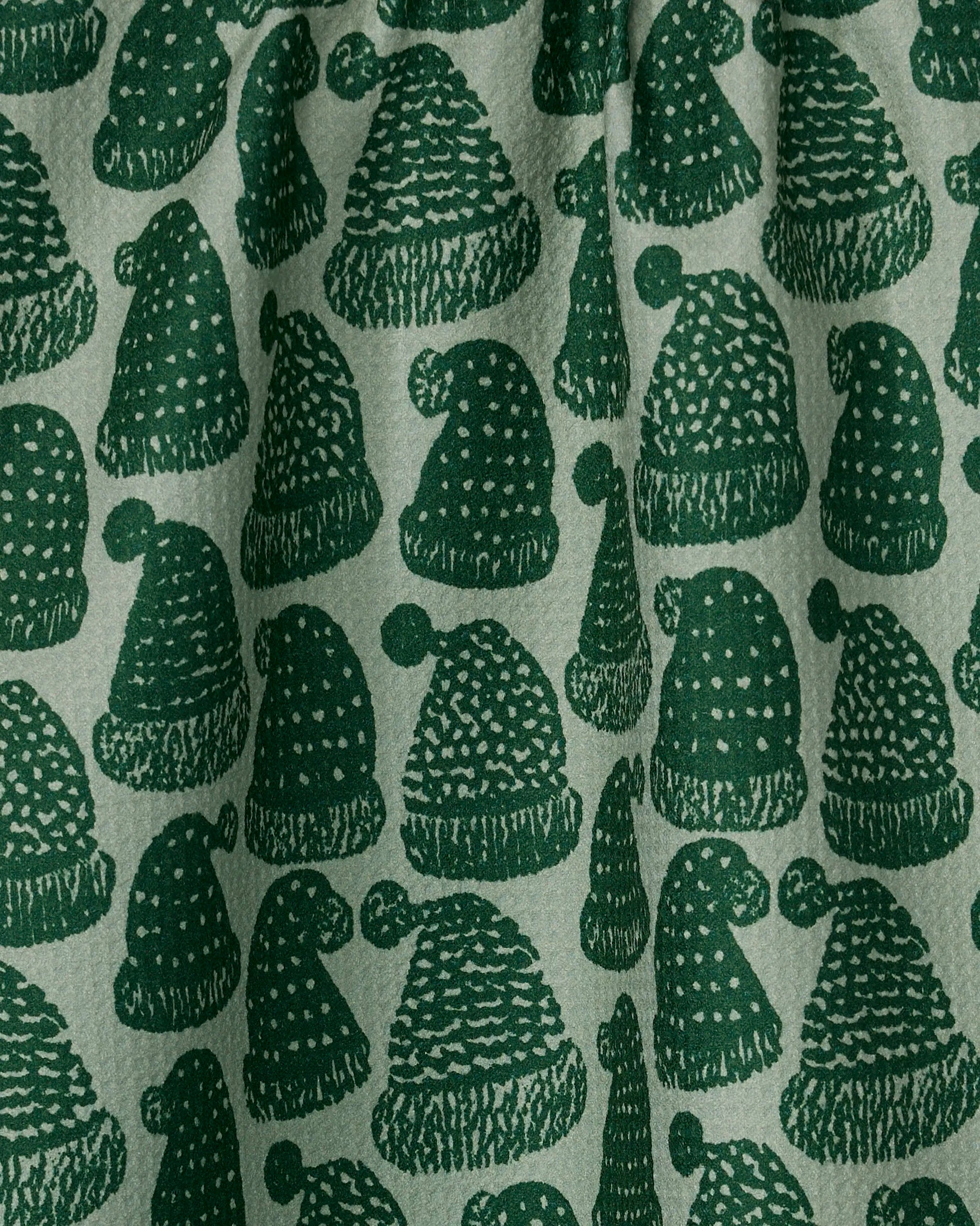 Frostcap Green by Geometry features ultra-absorbent fabric with a festive pattern of green Santa hats and beanies in assorted textures, set on a light background—ideal for a holiday tea towel.