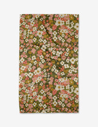 The Gilded Garden tea towel by Lisa Nelson features a vibrant floral pattern with pink, white, and yellow blooms on a brownish-green background, and is crafted from recycled materials.