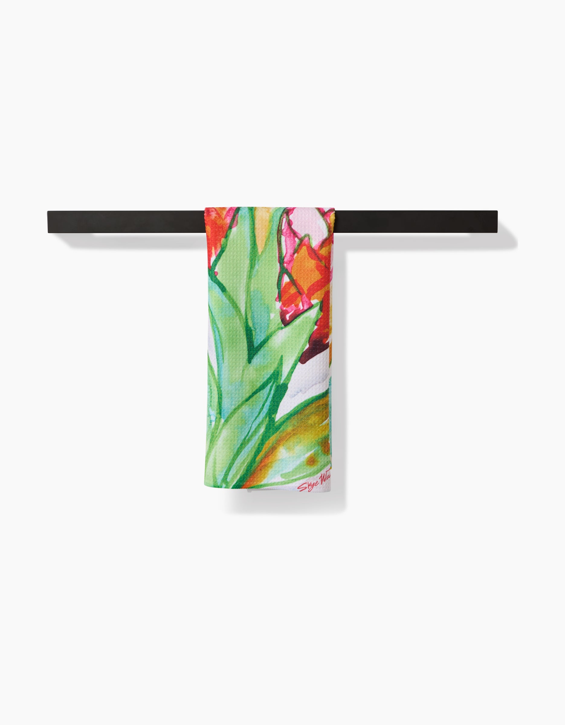The Skye Walker Ginger towel, featuring a vibrant abstract floral pattern in green, red, and pink, hangs on a black bar against a white backdrop. Made from ultra-absorbent Geoweave fabric.