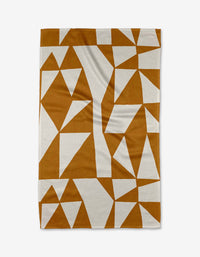 The Golden Angles blanket by Lisa Nelson is rectangular, made from recycled materials, and showcases a geometric pattern of brown and white triangles and polygons on a flat surface.