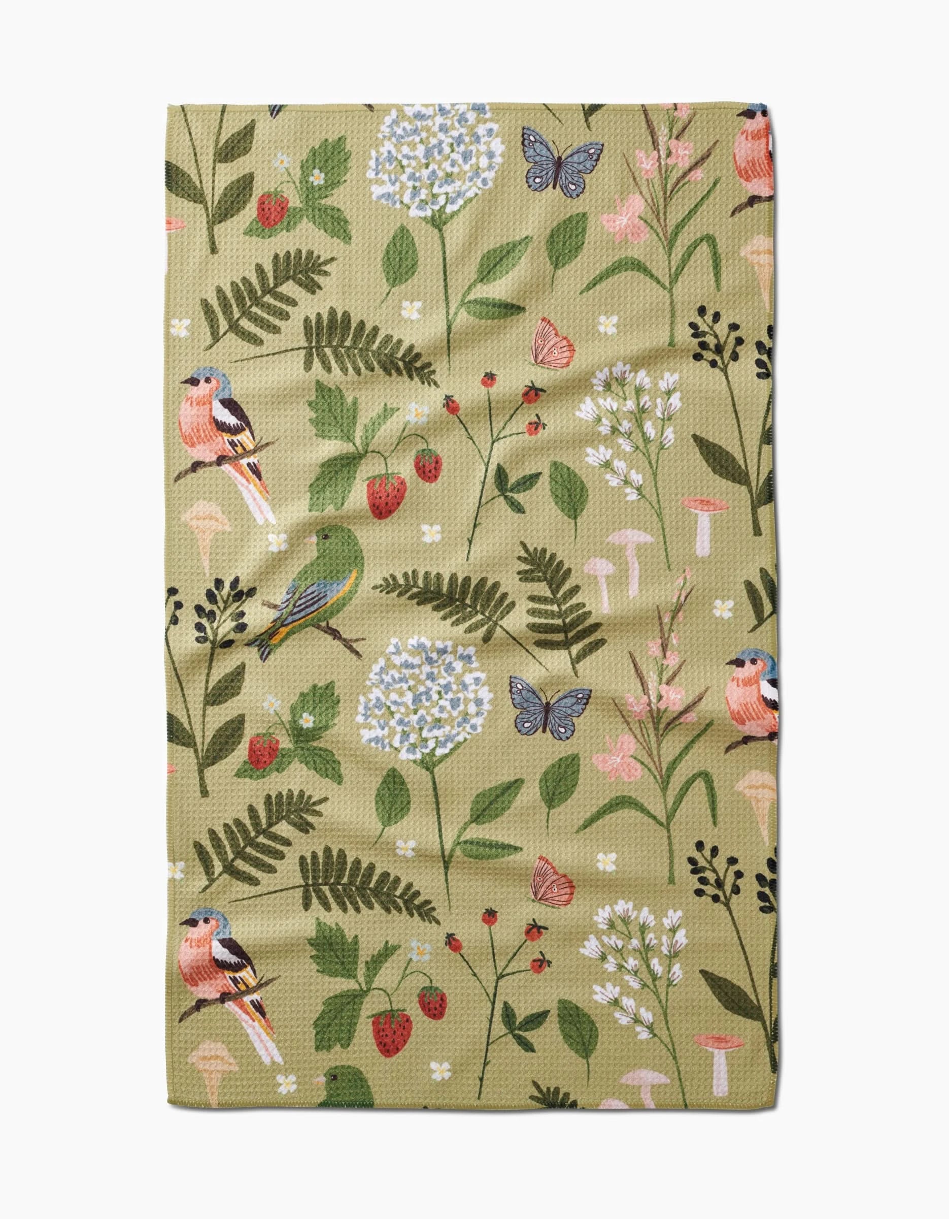 The Good Green Earth tea towel by Janna Sue Design is made from recycled materials and features an illustrated nature pattern with birds, butterflies, flowers, strawberries, mushrooms, and green leaves on a light olive Geoweave™ fabric.