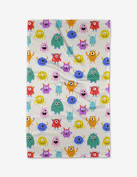 The Goofy Critters kitchen towel by Vaishali Design Studio features a vibrant pattern of cheerful cartoon monsters in bright colors on a white background, combining fun design with absorbent functionality.