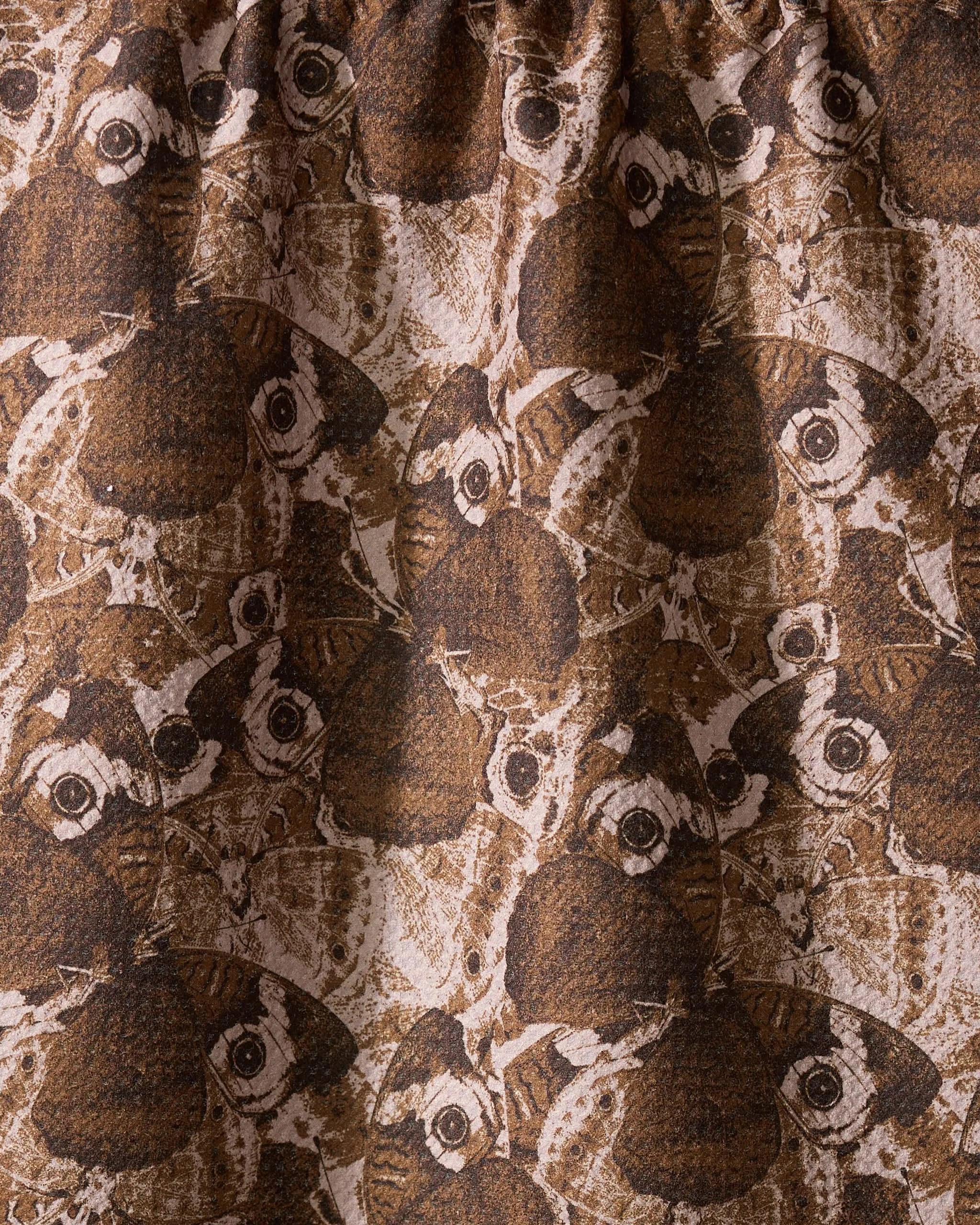 A close-up of Geometry’s Gossamer Flight tea towel showcases its Geoweave fabric, featuring overlapping brown and beige moths with detailed wings and eye spots for a textured, intricate design.