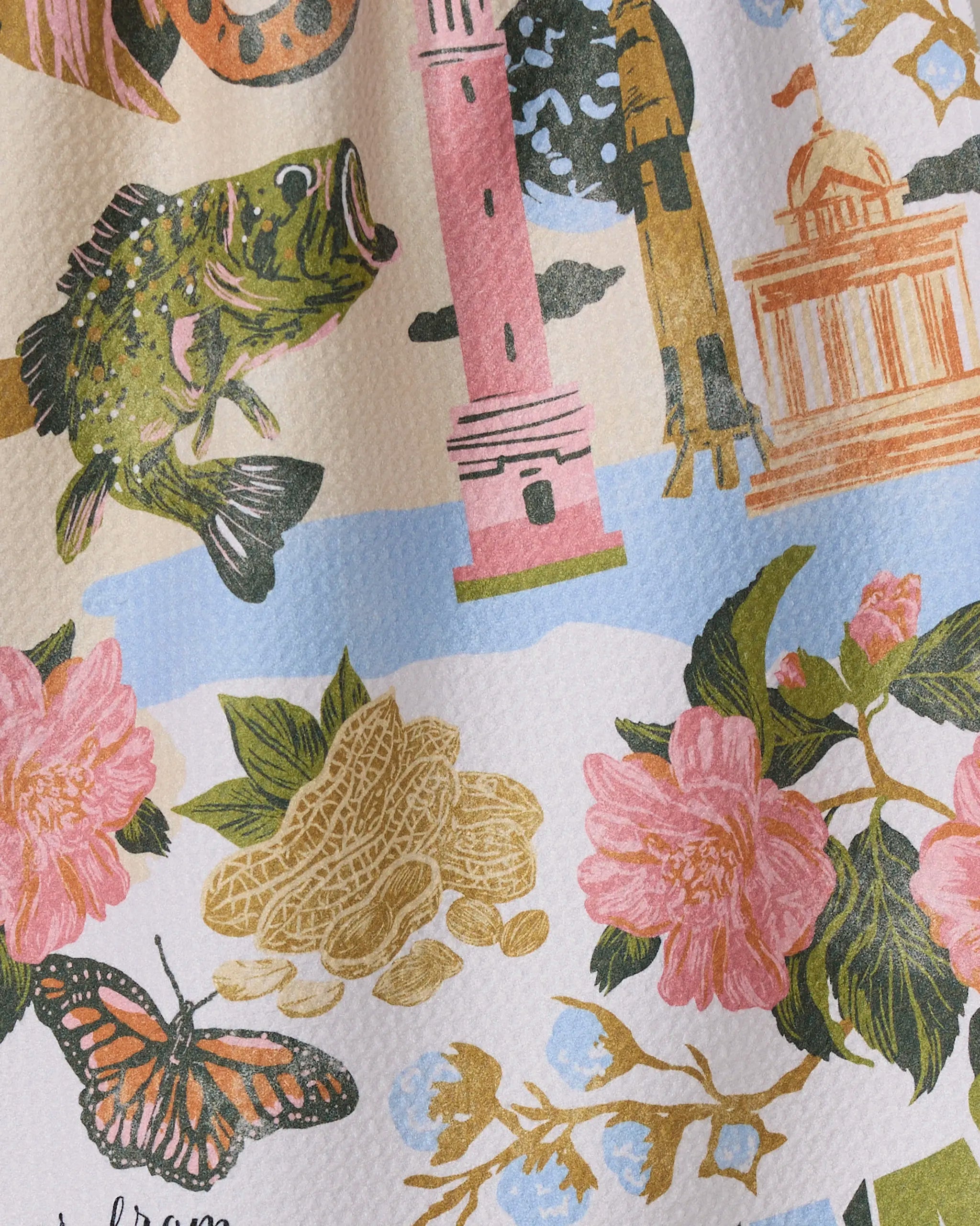 Illustrated image of a fish, peanuts, pink flowers, butterfly, pink lighthouse, domed building & trees on a textured background—perfect for the ultra-absorbent "Greetings From Alabama" tea towel by Geometry made from recycled materials.