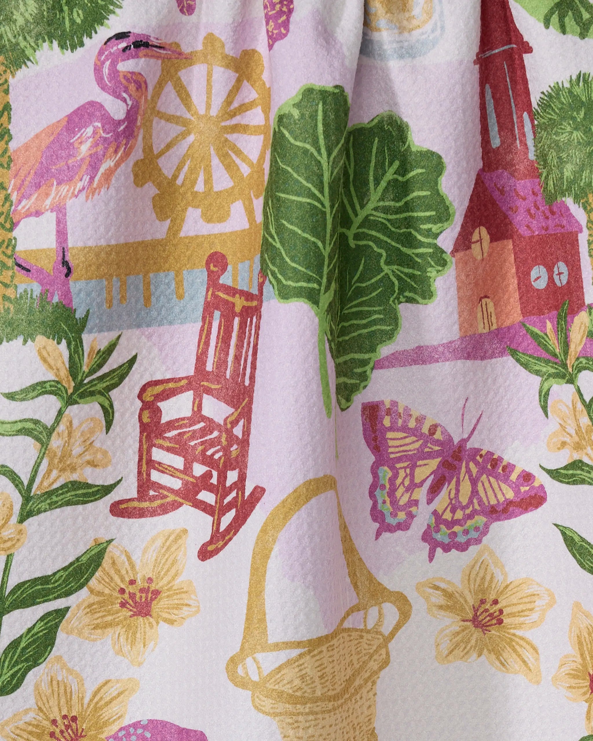 The Geometry "Greetings From South Carolina" recycled kitchen towel features colorful illustrations of a heron, Ferris wheel, green leaves, church, rocking chair, butterfly, yellow flowers, and a woven basket on a light background.