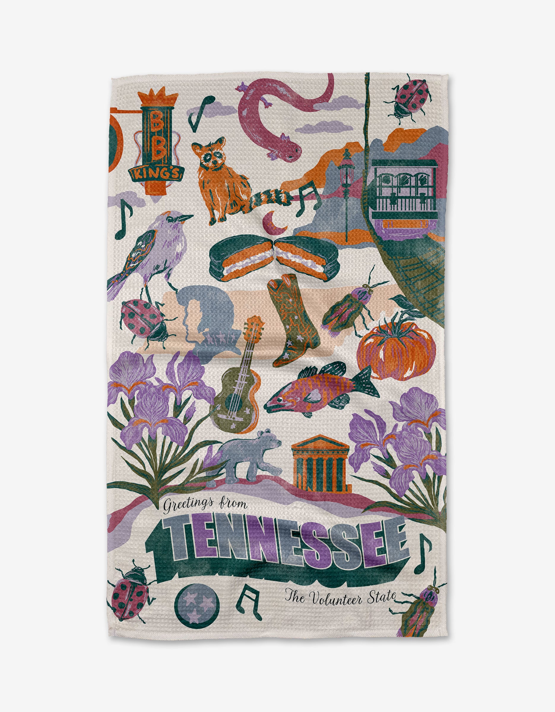The Geometry "Greetings From Tennessee" tea towel features colorful illustrations of state icons like musical notes, trains, flowers, guitars, raccoons, BBQ, B.B. King’s sign, ladybugs, rivers, and “The Volunteer State” on quick-drying fabric.