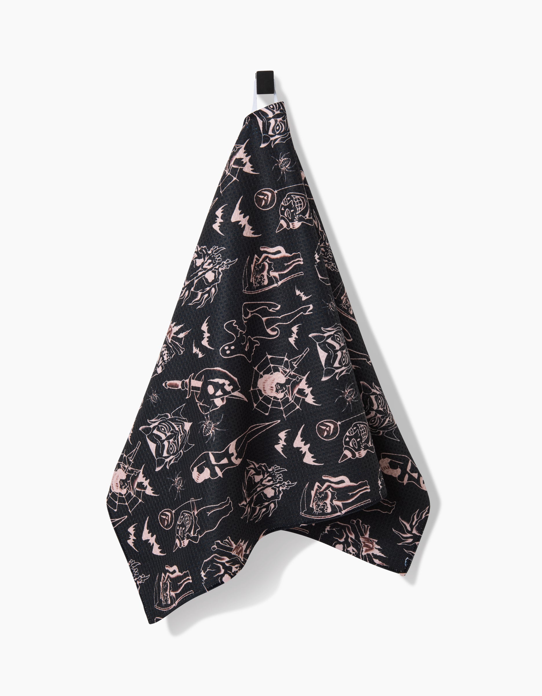 A black Cole Strem Halloween Flash tea towel, featuring pink, sketchy animal and object illustrations on Geoweave fabric, hangs from a black loop against a white background.