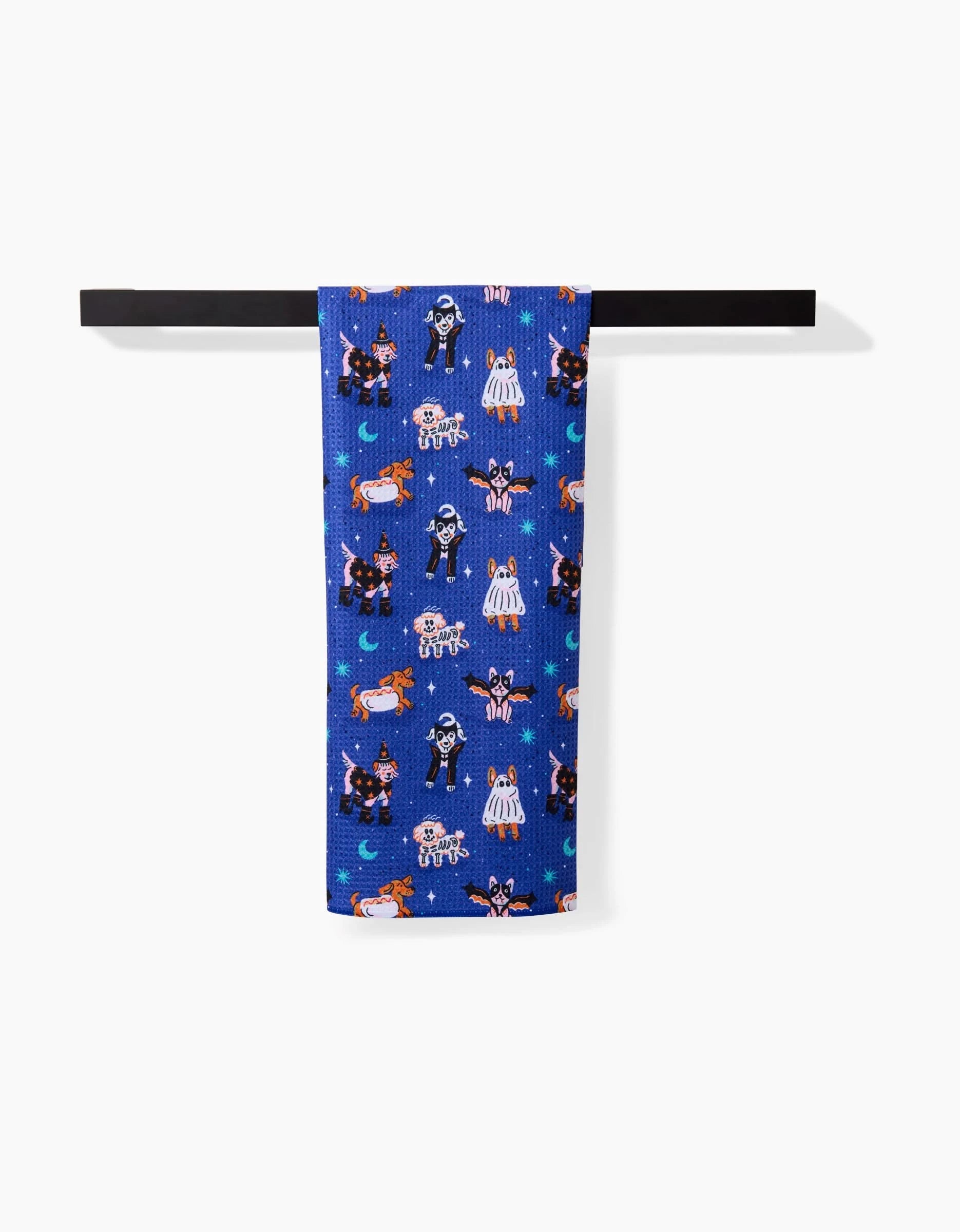 The Halloween Hounds tea towel by Camila Leão hangs on a black rod against a white background, showcasing cartoon dogs in Halloween costumes. Made from soft Geoweave fabric for extra absorbency.
