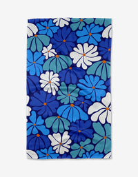 The Happy Fields dish towel by Rachel Parker is rectangular and absorbent, featuring a bright floral design with blue, teal, and white flowers with orange centers on a dark blue background.