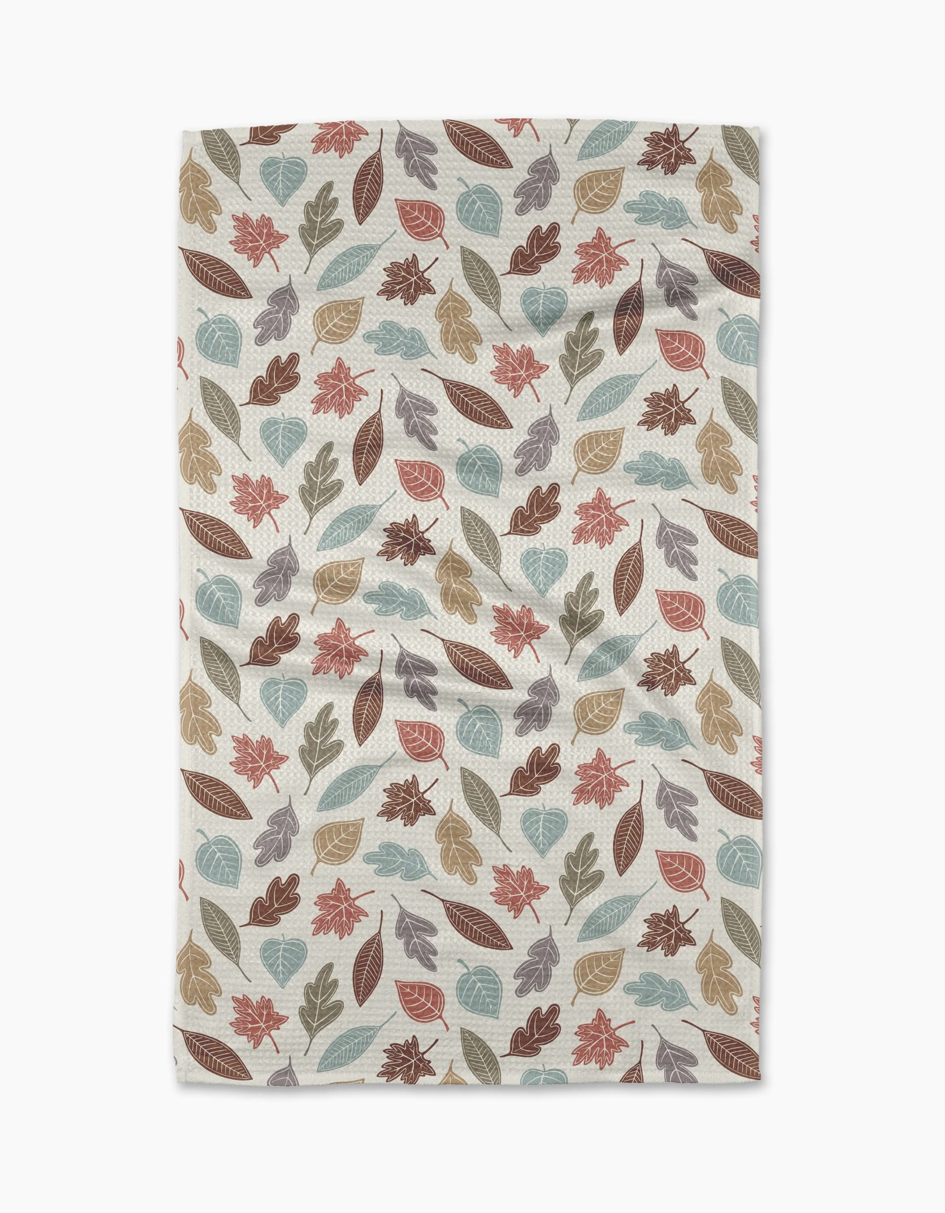 The Harvest Scatter tea towel by Sarah Daugherty features autumn leaves in brown, orange, teal, and beige on cream. Made from recycled materials, its slightly wrinkled finish gives a cozy, lived-in look.