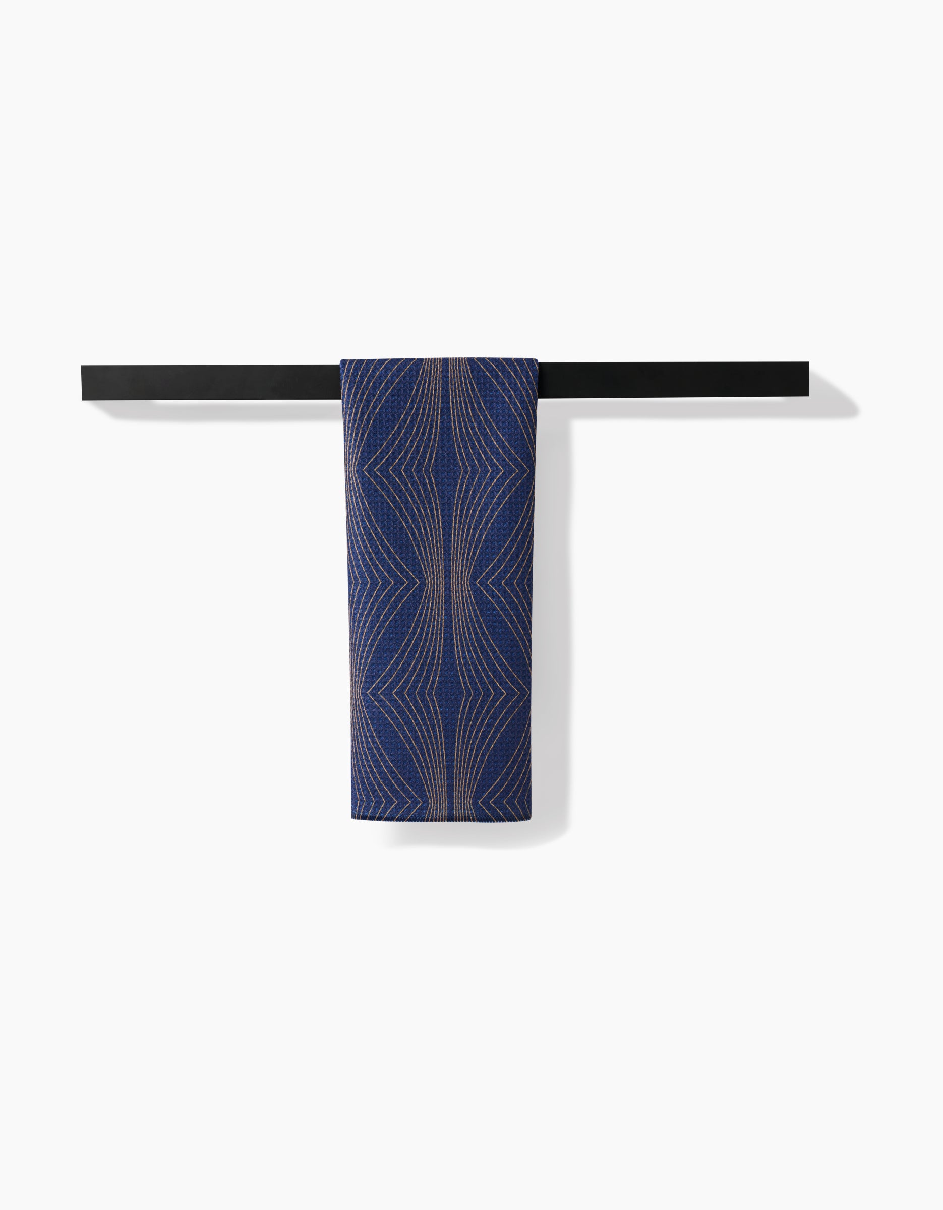 The Hera Tea Towel by Amy MacCready, featuring blue Geoweave™ fabric with beige geometric lines, is neatly folded over a minimalist black wall-mounted bar against a plain white background.