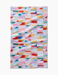 The Highlands tea towel by RACHEL PARKER features a vibrant geometric pattern of overlapping red, blue, yellow, pink, and green triangles and squares on white Geoweave fabric.