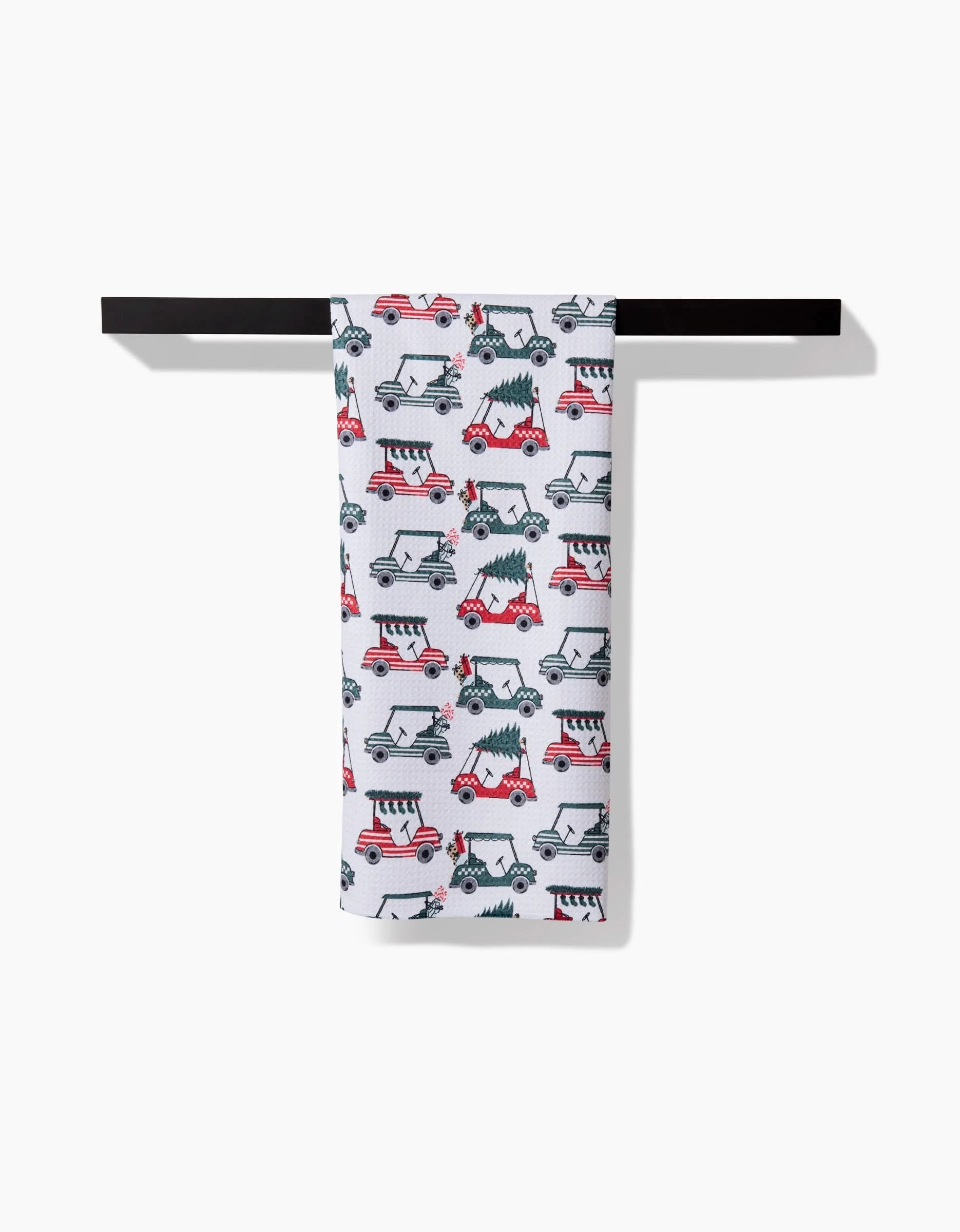 The Holiday Golf kitchen towel by Charlie Rowan Designs showcases a playful, repeating pattern of black and red illustrated dogs riding scooters, displayed on a horizontal black rod against a white background.
