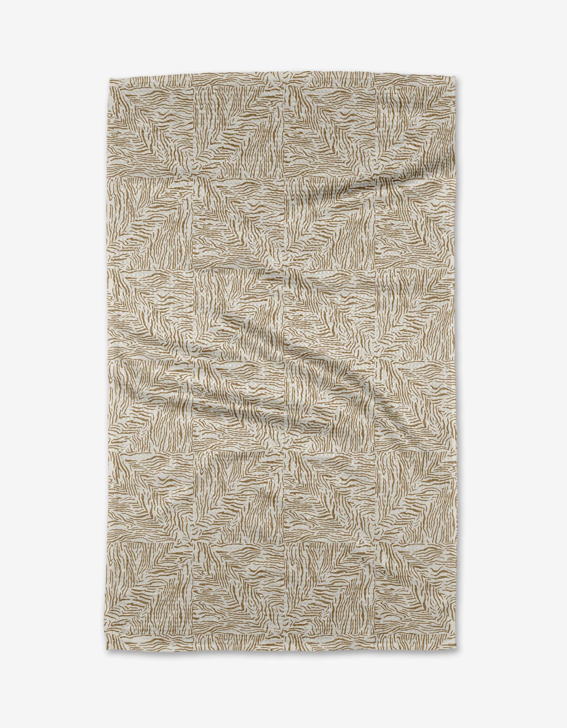 The Inlay tea towel by Studio Jeannot is crafted from Geoweave fabric and showcases a beige and white geometric zebra stripe pattern, laid flat on a white background with visible natural wrinkles and creases.
