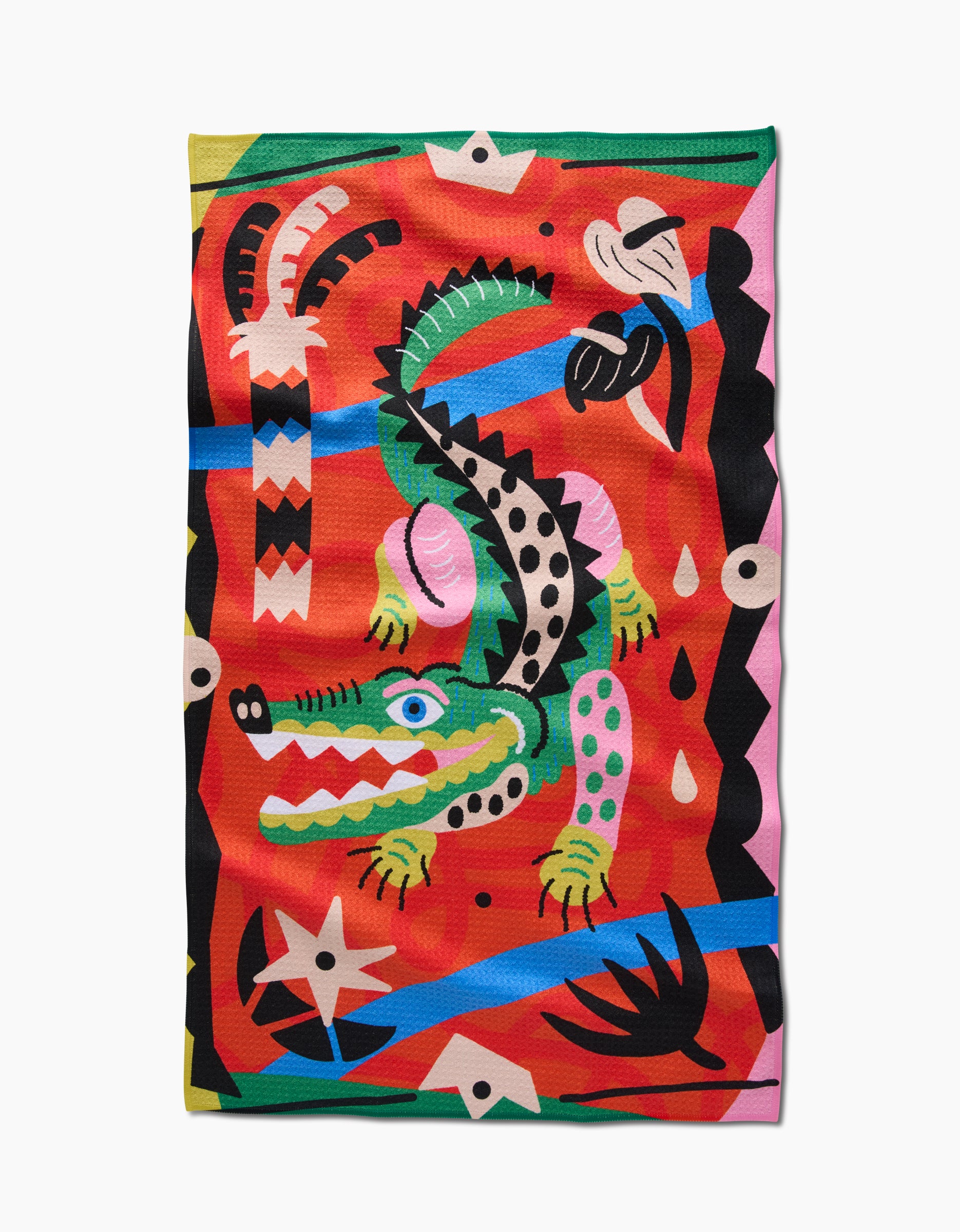 Jacaré by Camila Leão features a green crocodile with blue eyes and black spots on a vivid red background, surrounded by bold shapes in black, white, blue, and yellow. Printed on a Geoweave fabric tea towel.