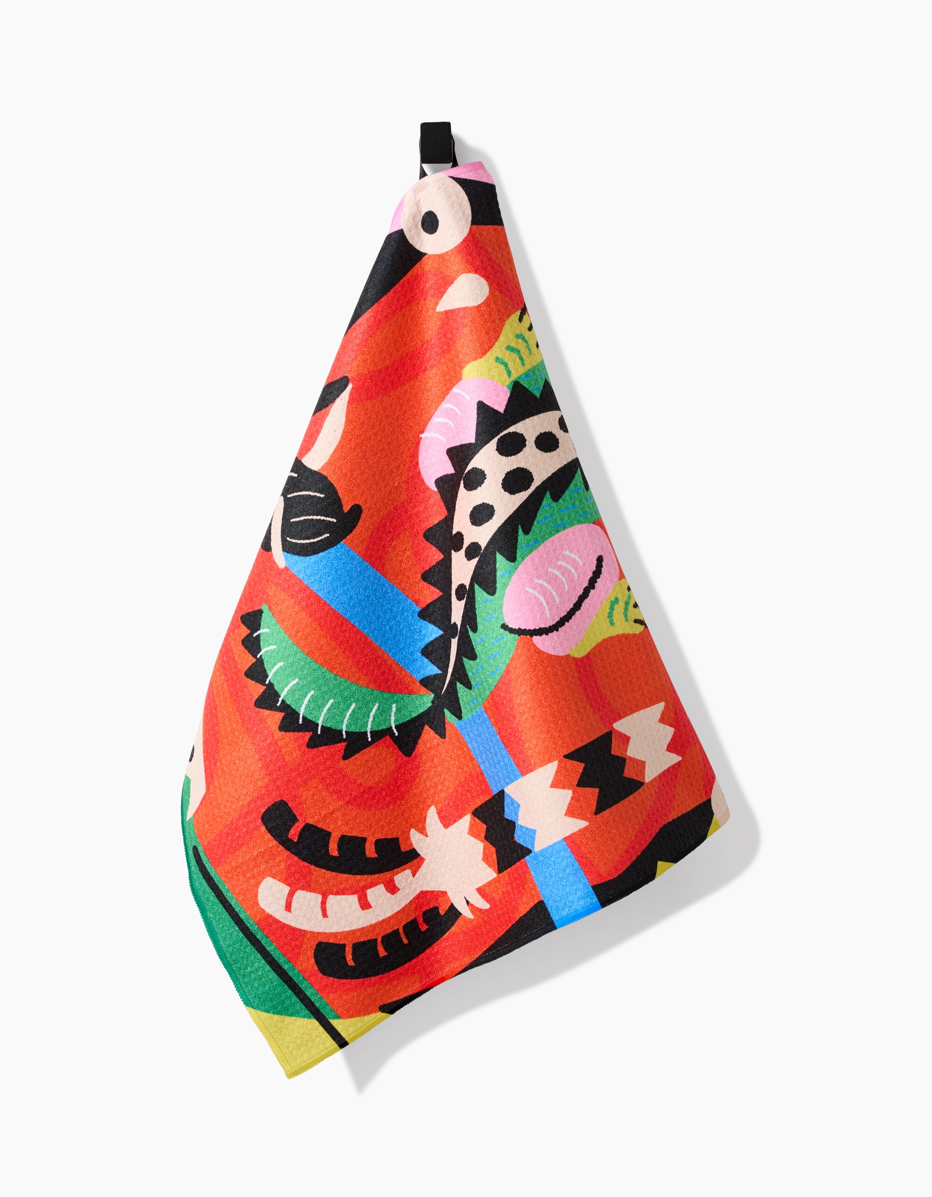 The Jacaré tea towel by Camila Leão showcases vibrant red Geoweave fabric with colorful abstract animal designs, including a leopard, and hangs on a hook against a white background.