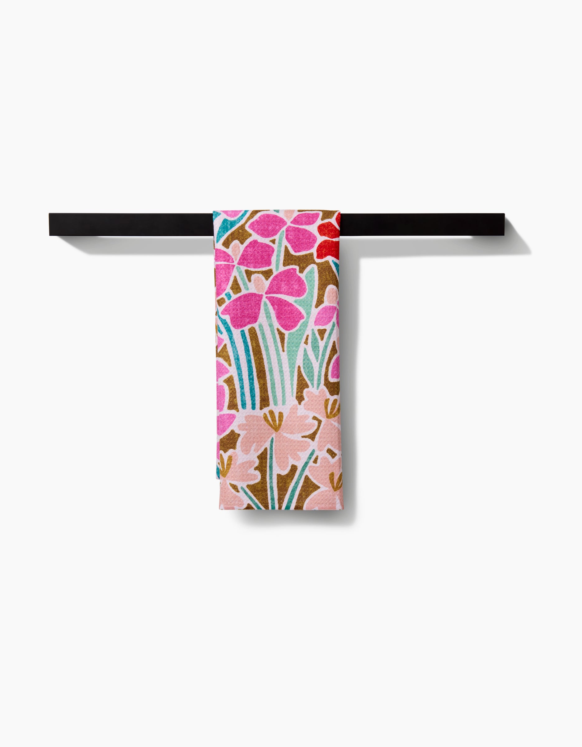 The Janae tea towel by Amy MacCready, featuring a pink and red floral design and made from recycled materials, is displayed on a black towel bar against a white background.
