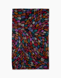 The Rachel Parker Jewel Leaf Swirl tea towel features a multicolored swirling leaf pattern on black, crafted from recycled materials. Vibrant shades of orange, purple, pink, red, blue, and green add dynamic style to your kitchen.