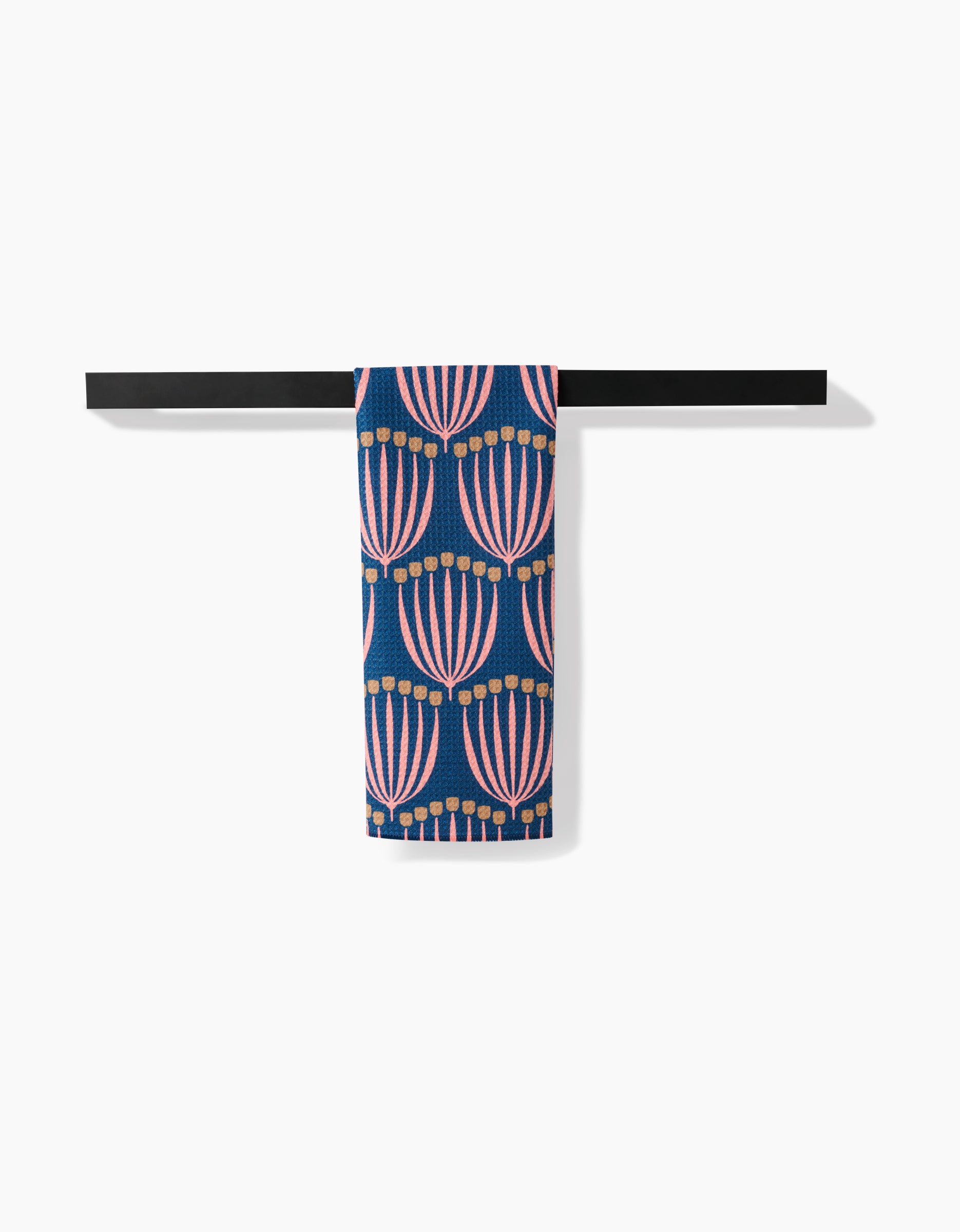 The Josie Geoweave™ tea towel by Amy MacCready, featuring pink and orange abstract florals on blue, hangs neatly over a black towel bar. Ultra-absorbent and stylish, it pops against the white backdrop.