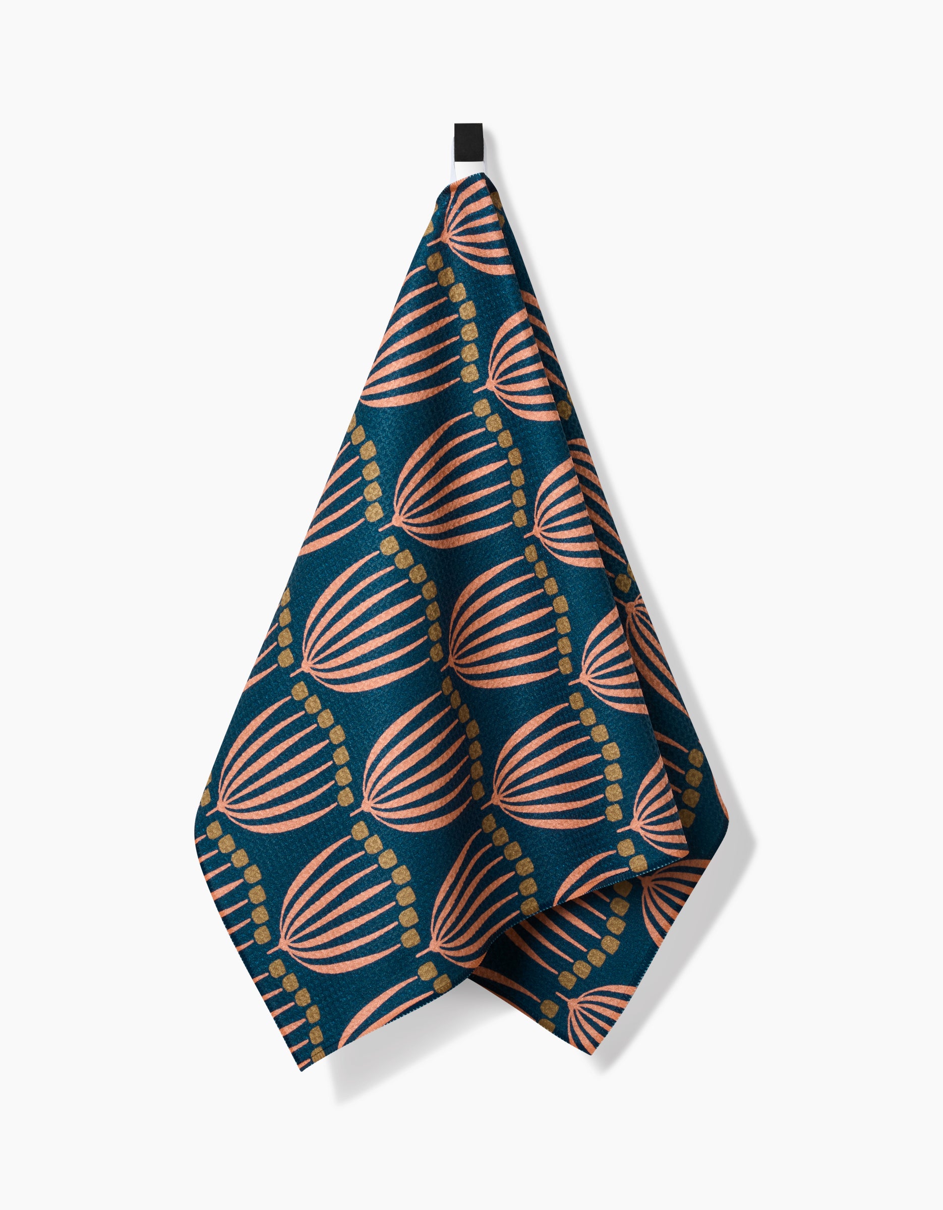 The Josie tea towel by Amy MacCready features dark blue Geoweave™ fabric with light pink and orange shell patterns and dotted gold lines, shown against a white background.