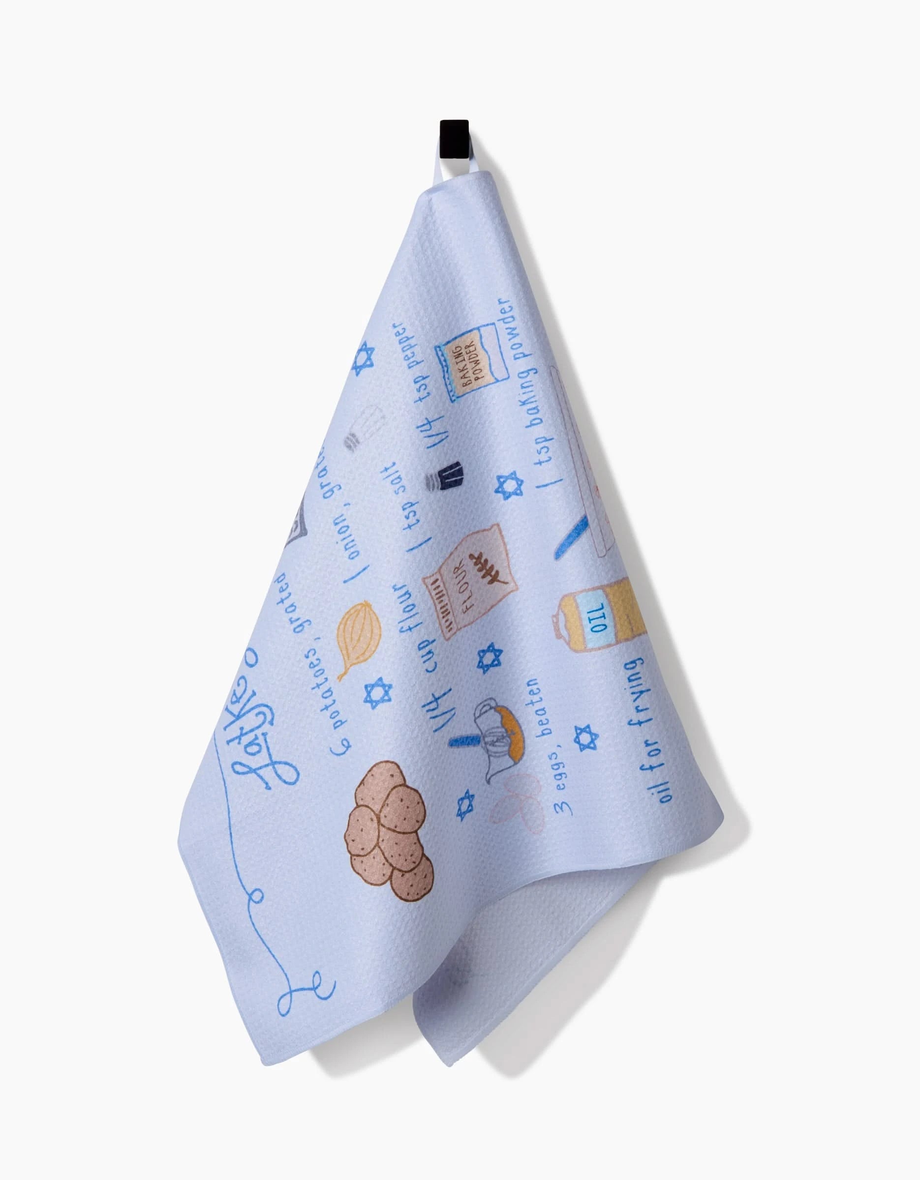 The Latke Love kitchen towel by Mindfulnice is light blue, made from recycled materials, and displays illustrated Jewish holiday foods and symbols with blue text and Star of David motifs. It hangs from a black loop against a white background.