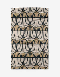 The Letitia tea towel by Amy MacCready features a cream and beige fan-like geometric pattern in black, arranged in horizontal rows. Made from recycled materials, its ultra-absorbent fabric has a slightly wrinkled look.