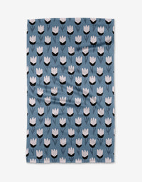The Lush Meadow tea towel by Anette Heiberg features white and black tulip-like flowers in rows on blue Geoweave fabric—ultra-absorbent for both style and function.