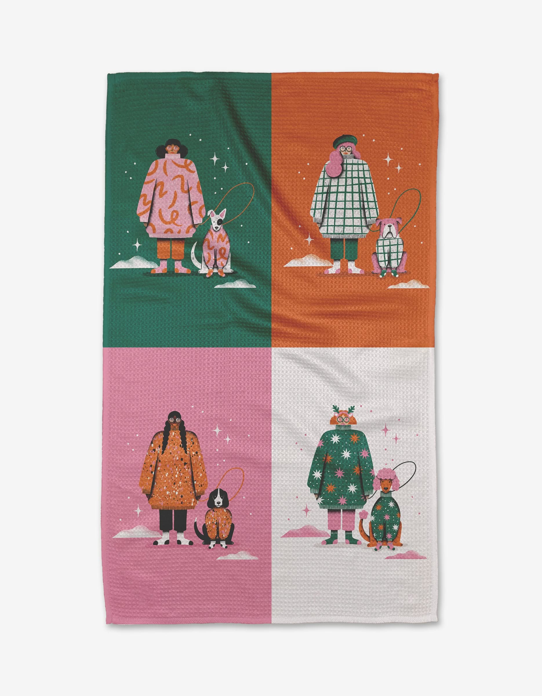 Matching Sweaters by Megan Roy is an eco-friendly kitchen towel featuring four sections, each with a person and dog in winter outfits against green, orange, pink, and white snowy backgrounds dotted with stars.