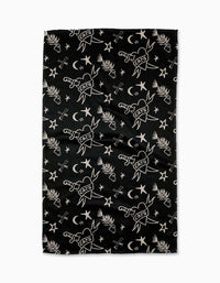 The Meow or Never Tea Towel by Cole Strem is a black Geoweave towel made from recycled materials, featuring white illustrations of swords labeled CATS, crescent moons, stars, palm leaves, and crossed arrows.