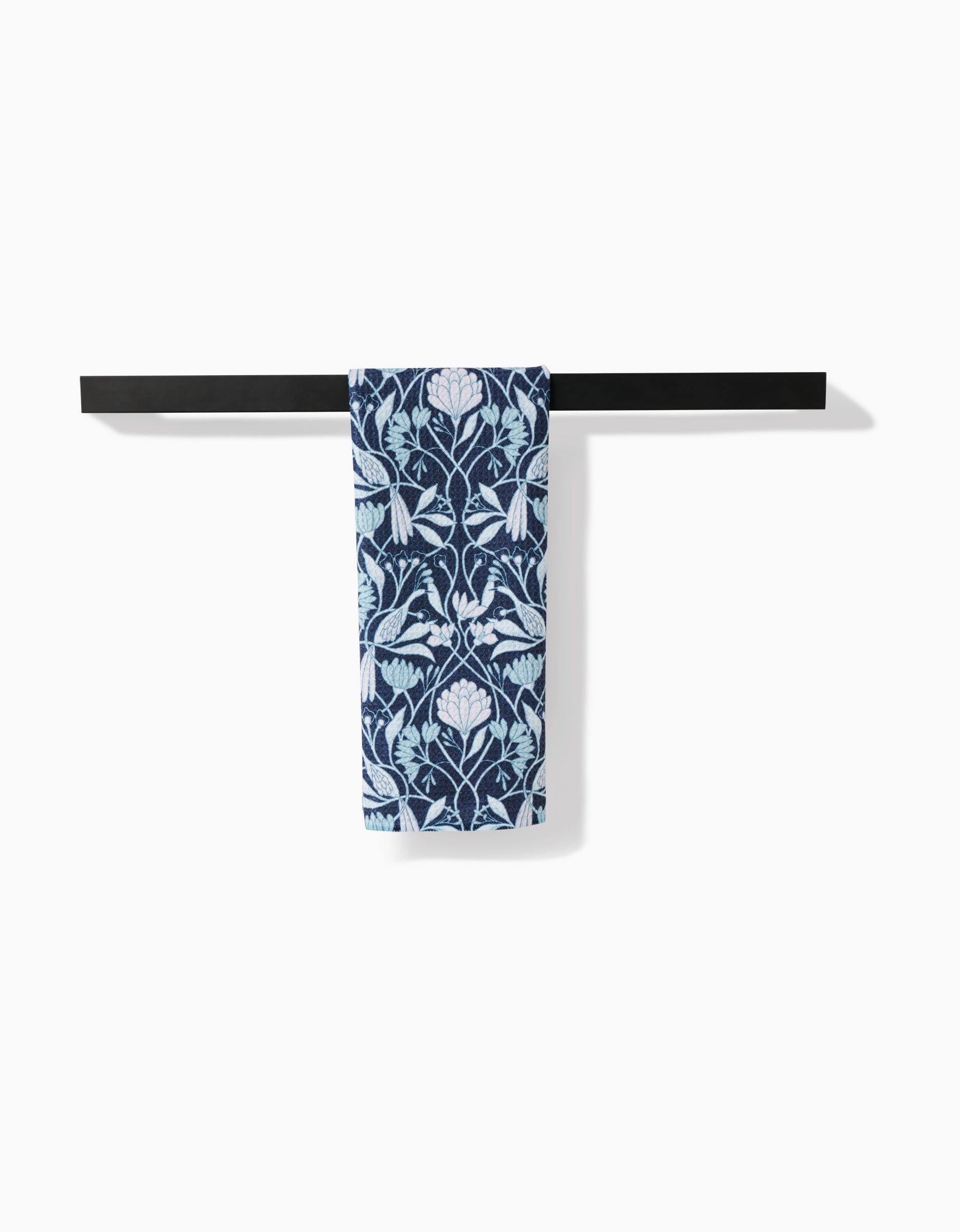 The Amy MacCready Mirielle towel, featuring a blue and white floral pattern in ultra-absorbent Geoweave fabric, hangs on a sleek black bar against a plain white background.