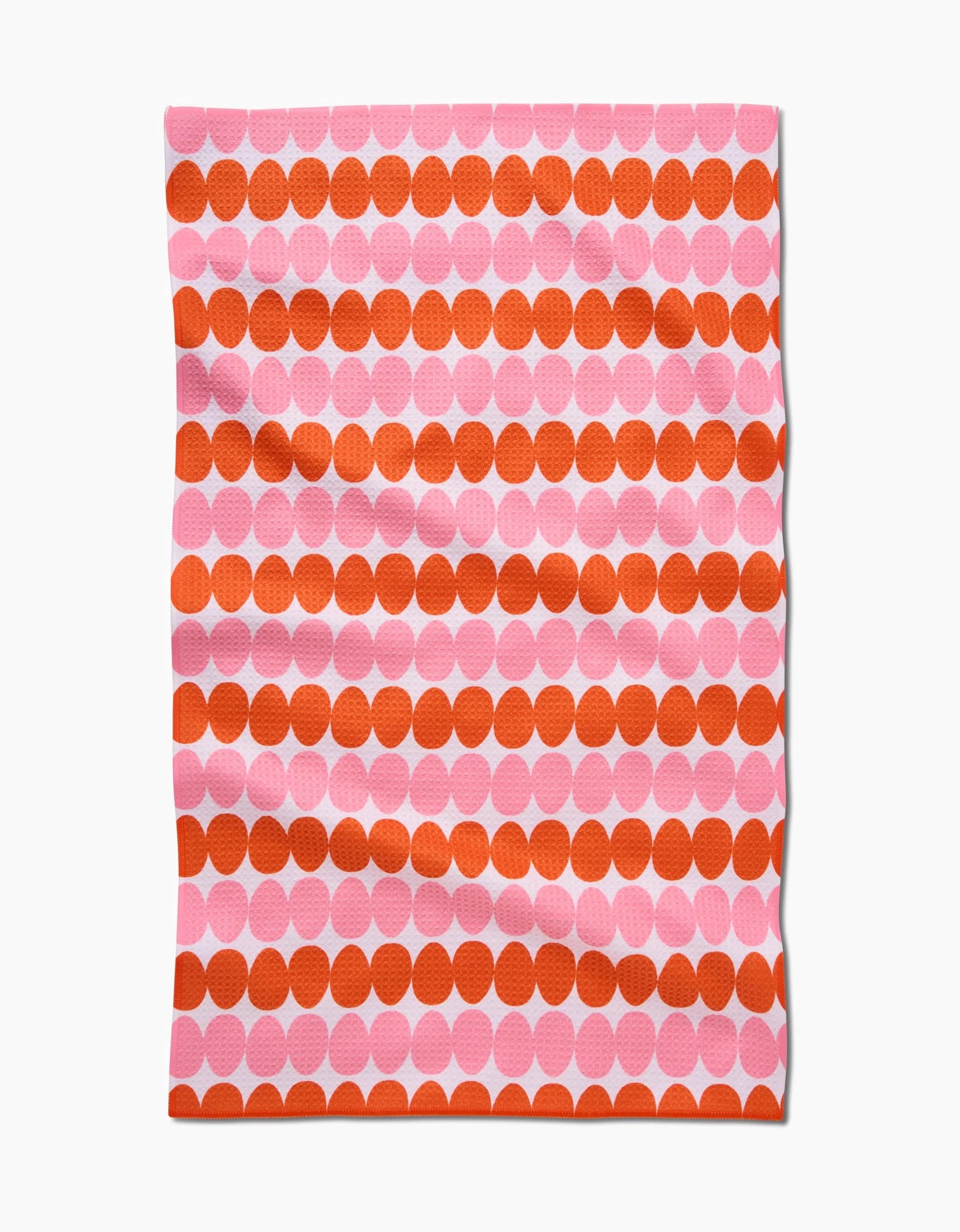 The Kayla Ann Modd Egg is a rectangular Geoweave tea towel featuring large orange and pink geometric dots on a light background. Made from recycled materials, its soft wrinkles create a relaxed, modern look.
