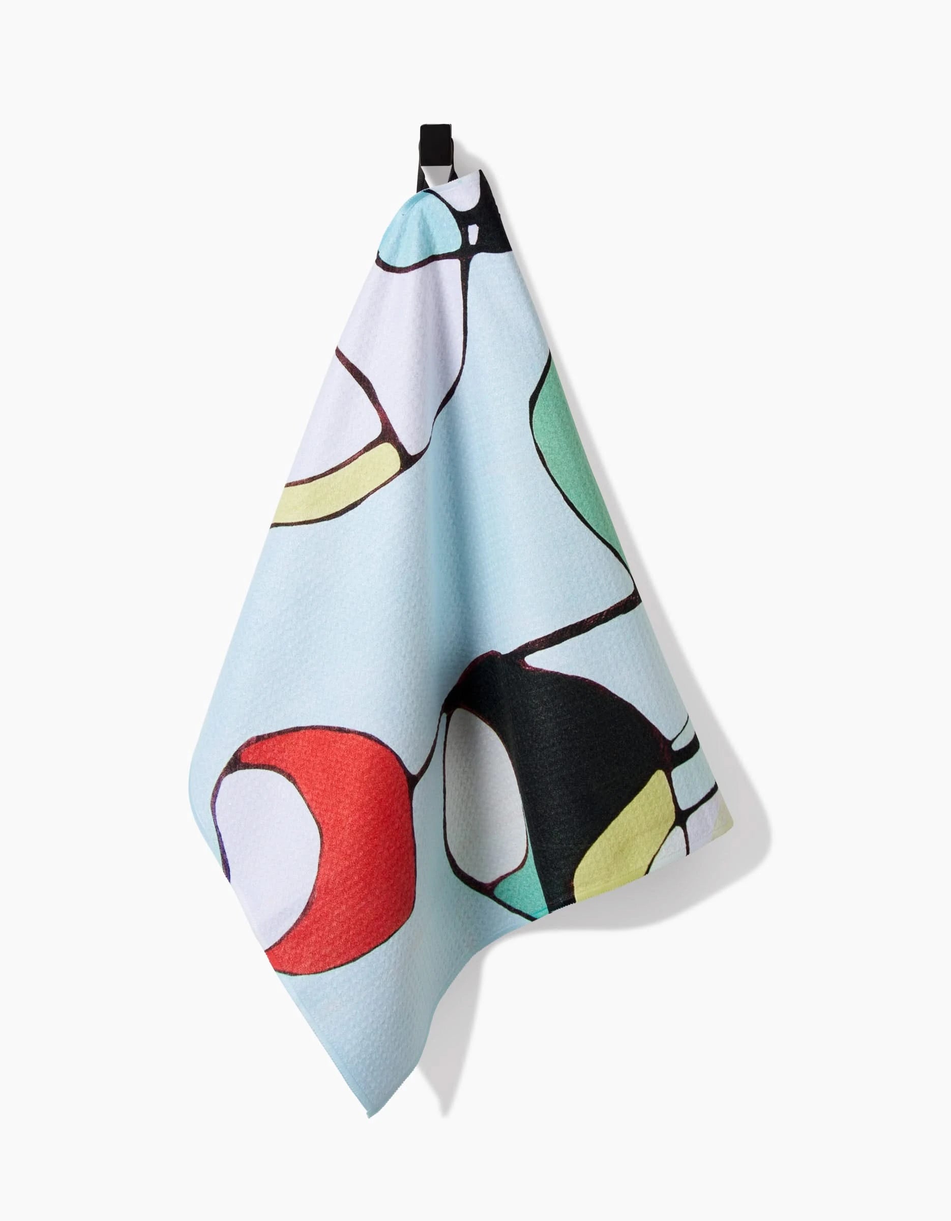 A light blue Modern Poppy tea towel by Rachel Austin, featuring abstract red, green, yellow, black, and white patterns on Geoweave fabric, hangs from a black loop against a white background.