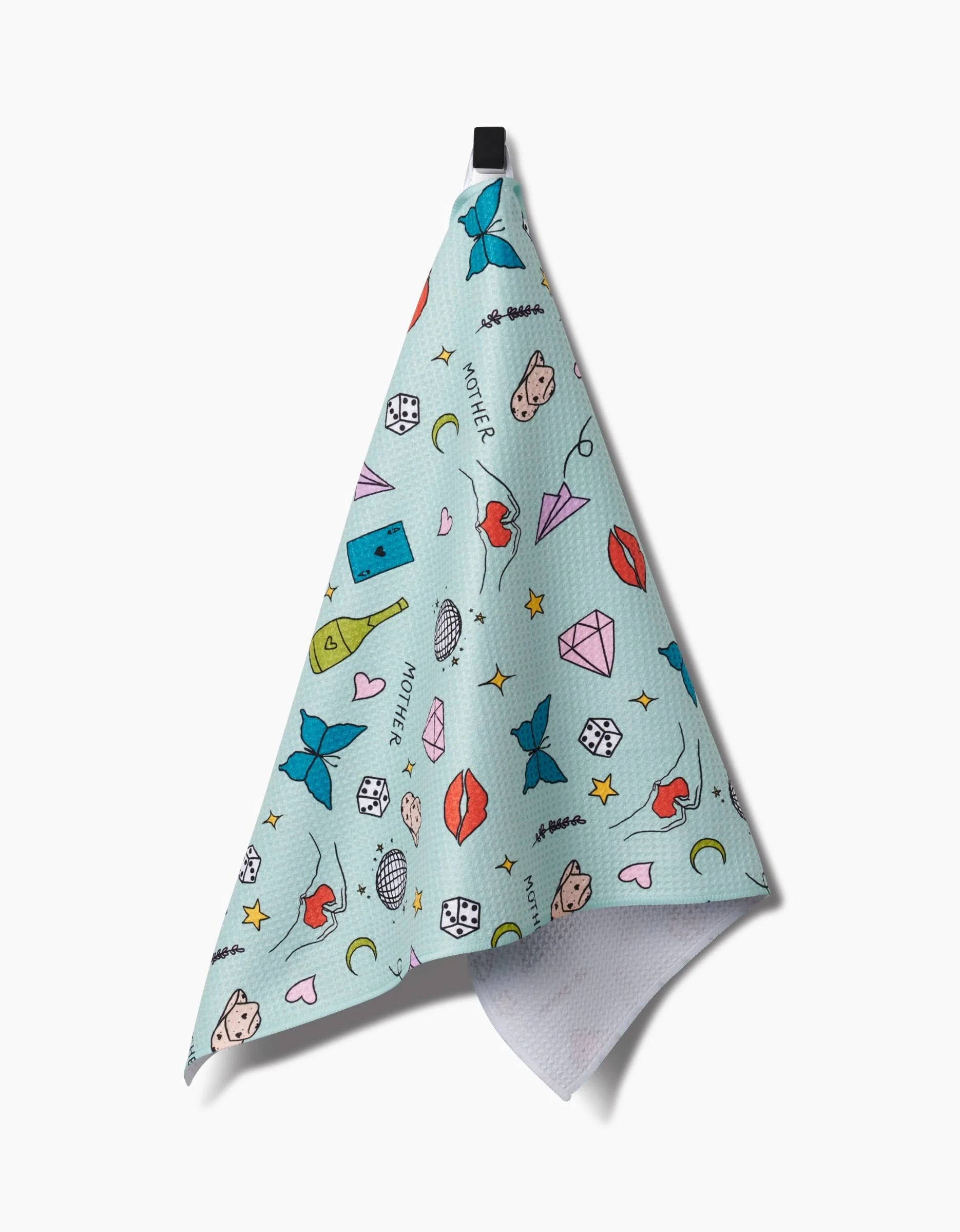 The Mother towel by Sarah Holden is a light blue, ultra-absorbent Geoweave towel featuring colorful cube, lip, diamond, moon, star, heart, and cartoon face doodles. It hangs from a black loop against a white background.