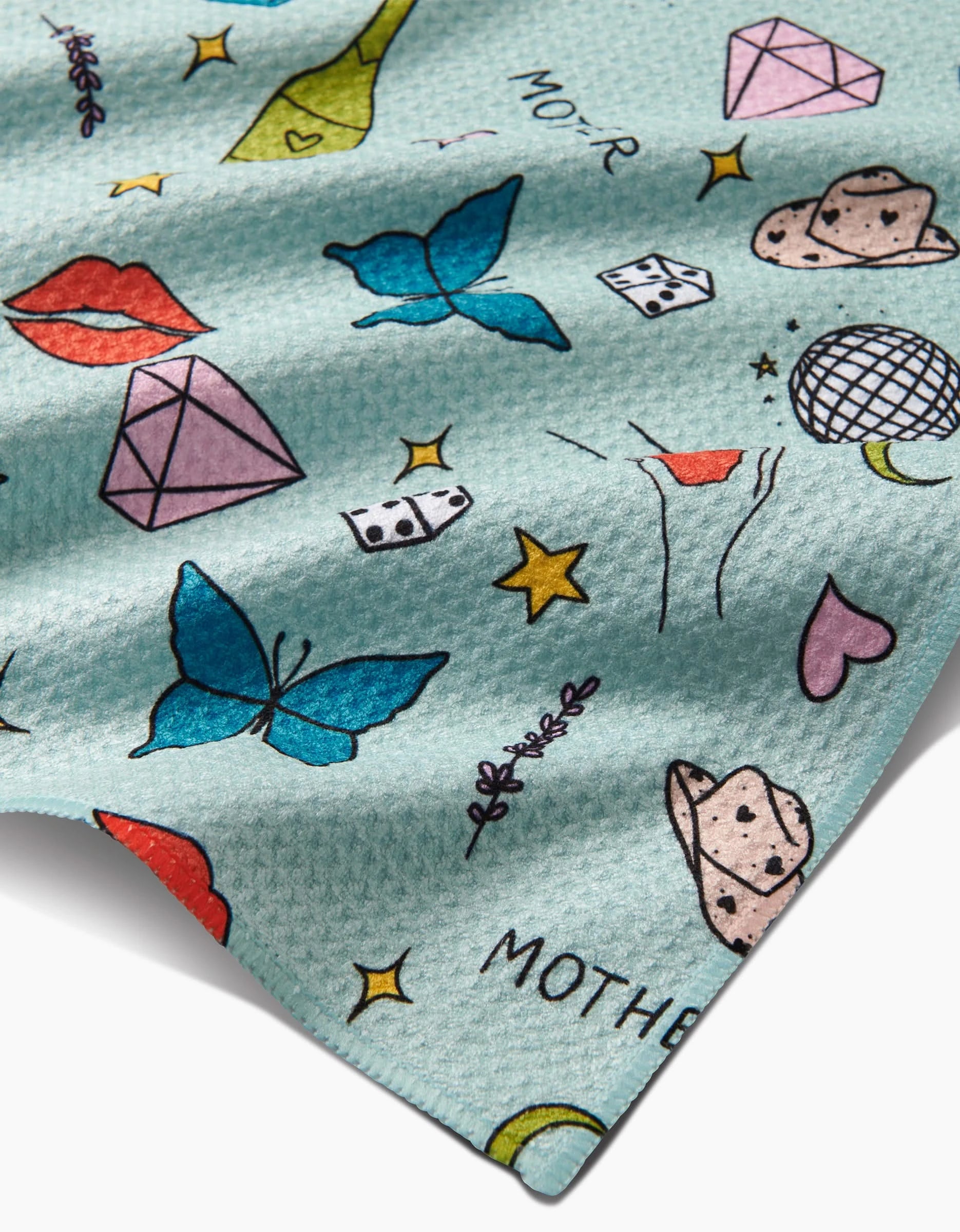 Mother by Sarah Holden: A blue Geoweave fabric with playful prints—butterflies, diamonds, lips, cowboy hats, a disco ball, dice, stars, moons, martini glasses—and the partial word MOTHER. Made from recycled materials.