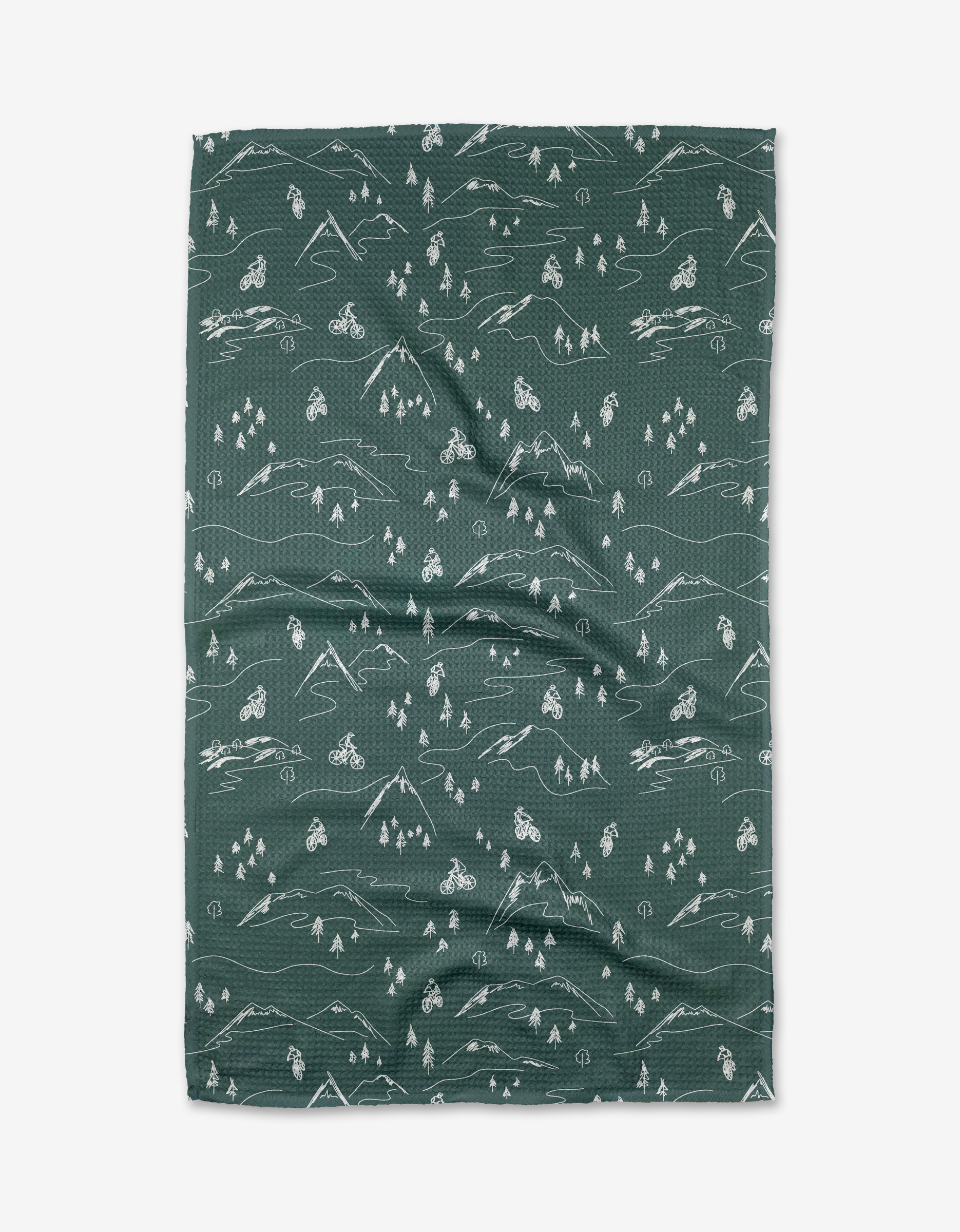 The Coit Creative Mountain Biking blanket is green, rectangular, and made from Geoweave™ fabric, featuring white line drawings of mountains, trees, bicycles, and tents in a repeating pattern on a white background.