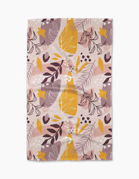 The Cottonflower Studio Nature Sketch tea towel is a rectangular, ultra-absorbent dish towel with an abstract botanical pattern of leaves, berries, and broad shapes in yellow, white, brown, and mauve on pale pink.
