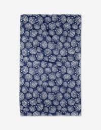 The Kris Ruff Nautical Seashells tea towel is a dark blue rectangle made from recycled materials, featuring a repeating white spiral seashell pattern across the entire surface.