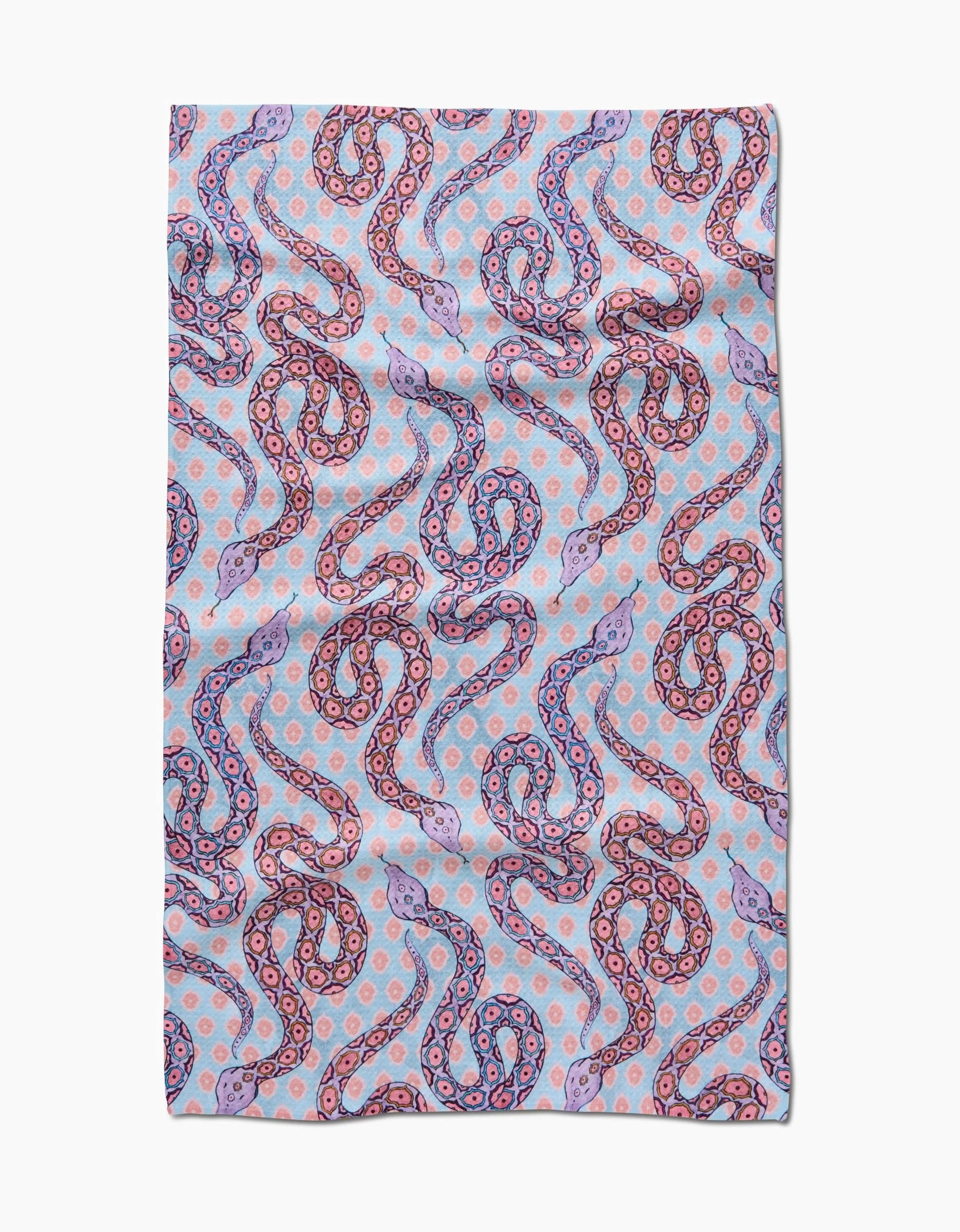 The Ophidia tea towel by Maayan Alper-Swan features colorful, stylized snakes in pink, purple, and blue with dotted accents. This light blue, rectangular towel is made from ultra-absorbent post-consumer recycled materials.