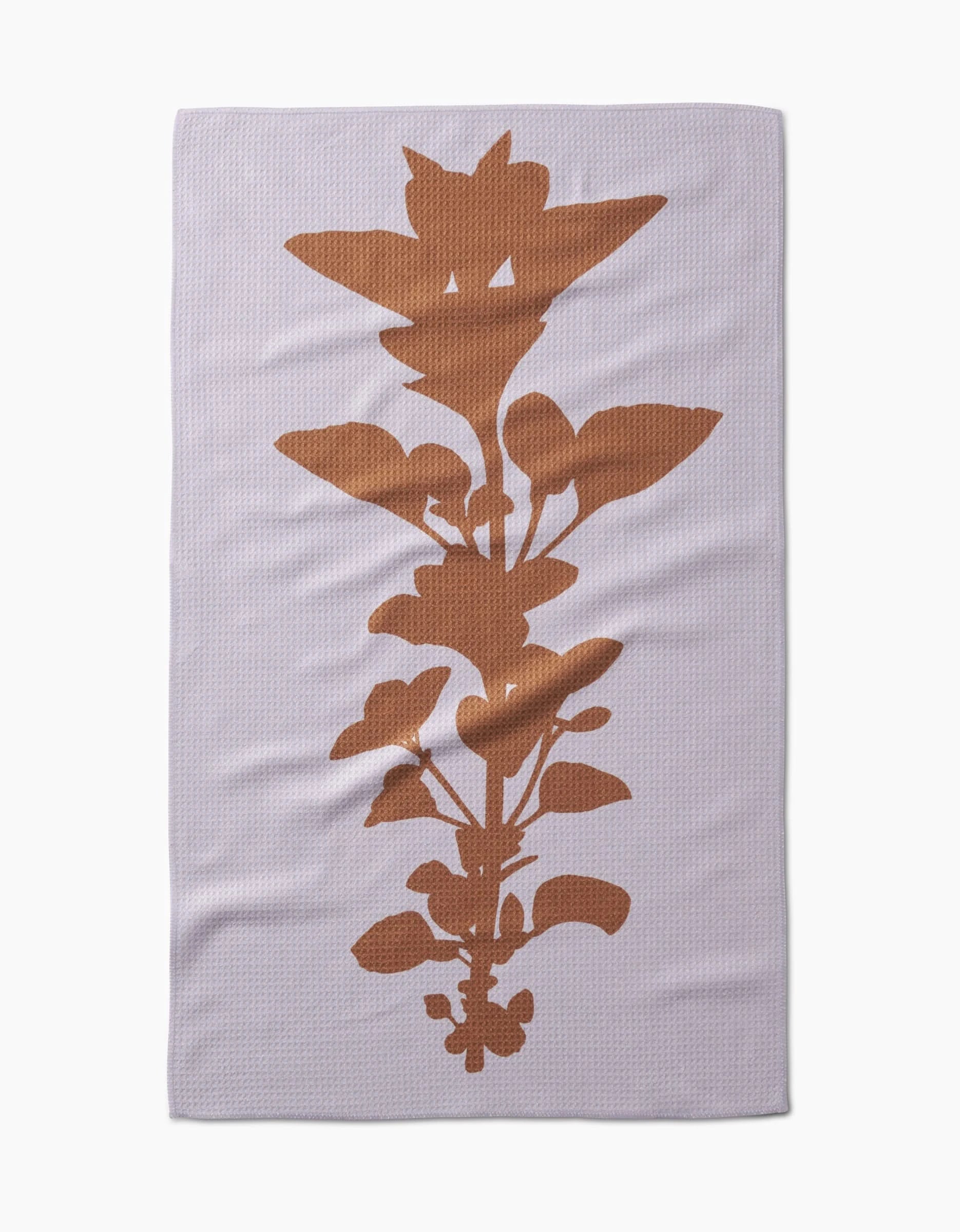 The PrintedPlant Oregano Tea Towel is pale lavender with a large, rust-colored oregano silhouette centered vertically, and is crafted from recycled materials.