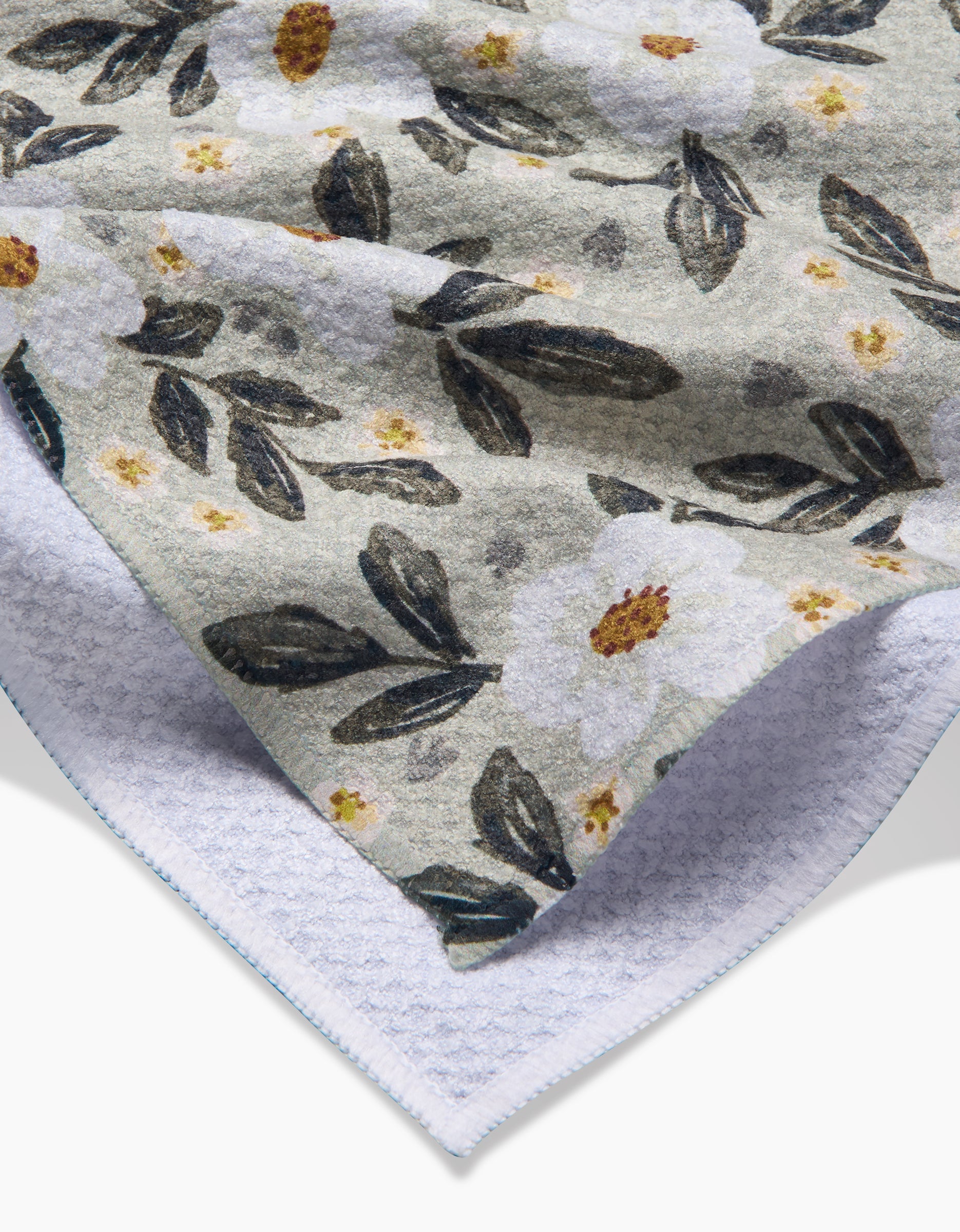 The Painted Spring Flowers blanket by Teri the Butter features a soft fleece side with white flowers and dark green leaves, plus a cozy white sherpa lining—crafted from recycled materials for eco-friendly comfort.