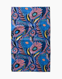 The Palm Beach tea towel by Masha Volnova features a vibrant floral pattern with large blue, pink, and yellow flowers and green leaves on a blue background, crafted from recycled materials.