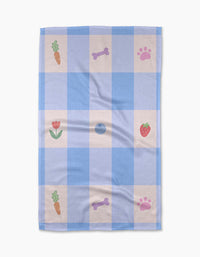 The Pawfect Picnic towel by Letters By Shells is a blue and white checkered, ultra-absorbent towel with carrot, strawberry, bone, paw print, and tulip patterns in some squares.