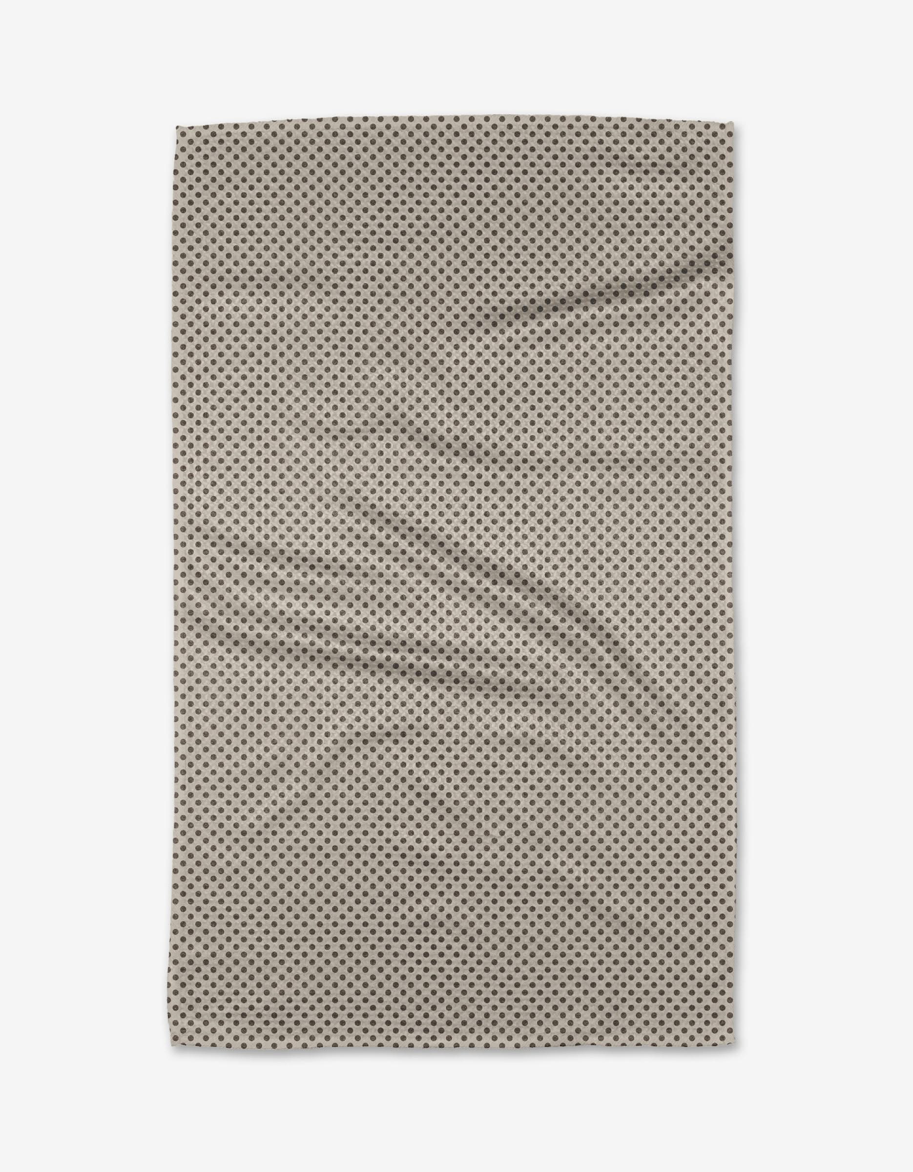 The Jenny Keller Pebble towel, a rectangular beige ultra-absorbent piece with small black polka dots, is laid flat to reveal gentle wrinkles and soft folds against a white background.