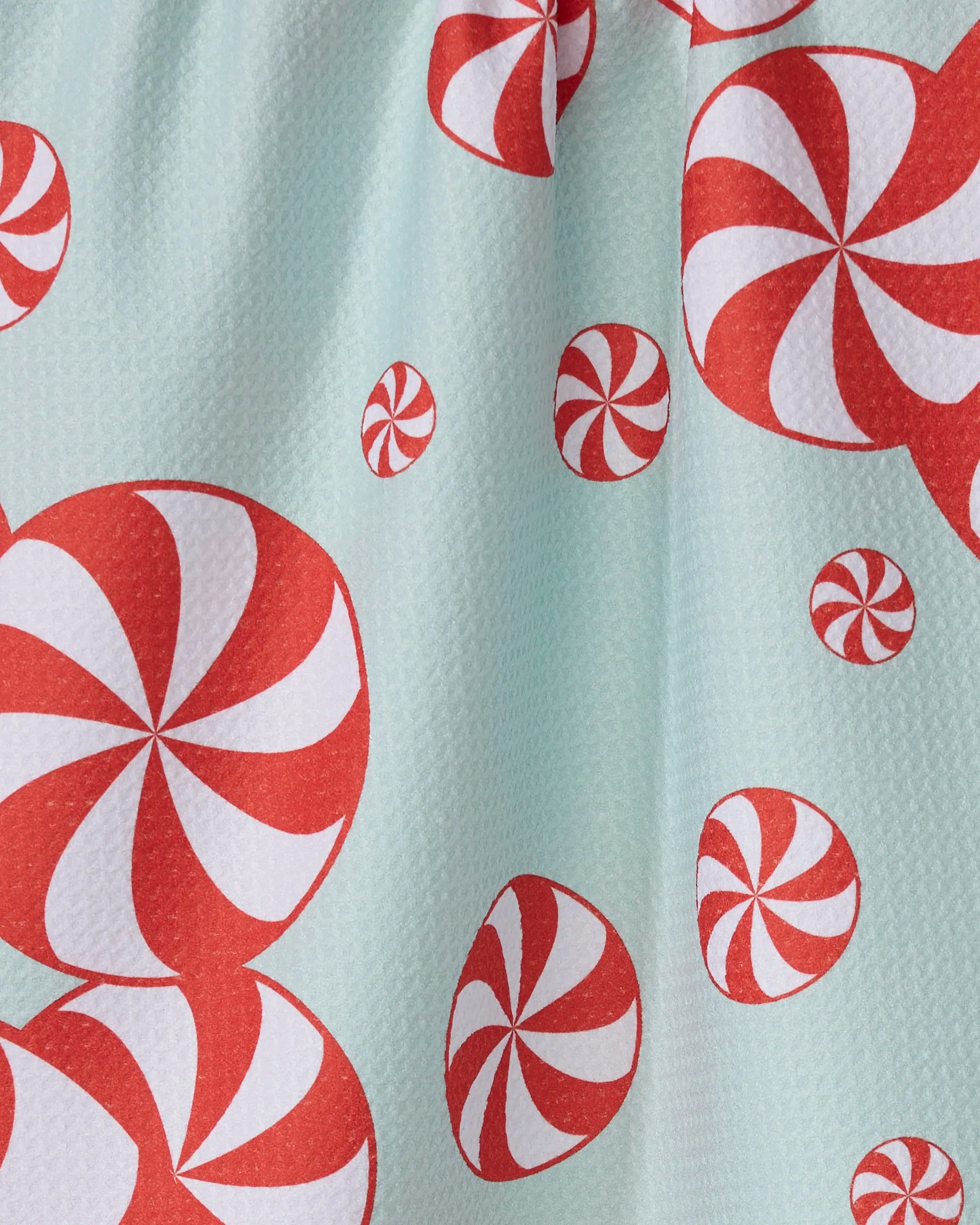 Close-up of Geometry’s Peppermint Swirl quick-drying fabric, featuring red and white peppermint candies of various sizes scattered on a light blue background—perfect for a festive tea towel.