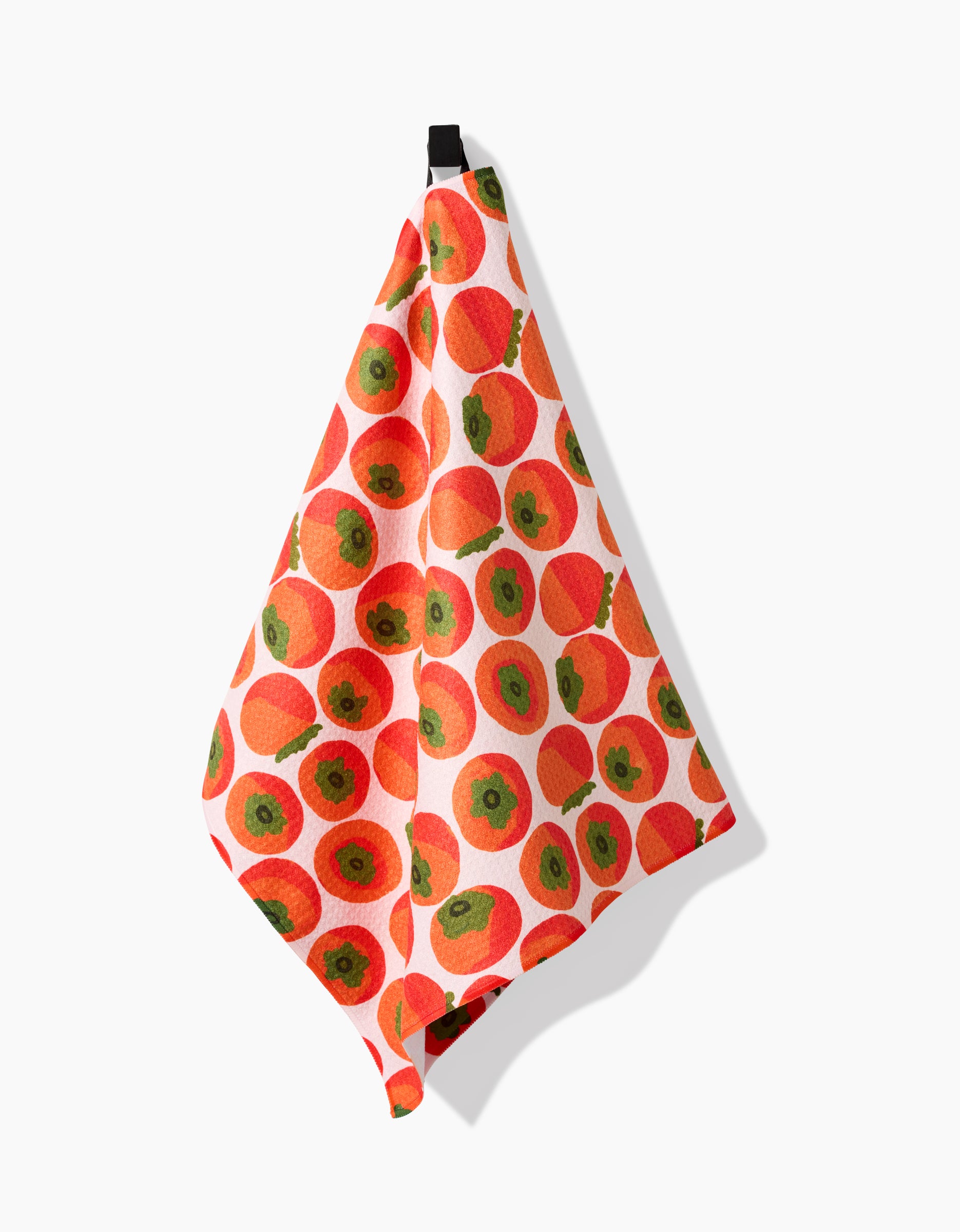 The Katie OShea Persimmons Kitchen Tea Towel, made from recycled materials and showcasing a persimmon pattern, hangs from a black loop against a white background.