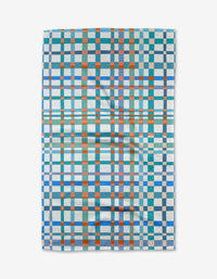 The Picnic Perfect tea towel by Rachel Parker features a grid of blue, teal, orange, and white checks. Made from recycled materials, the slightly wrinkled fabric is shown on a white background.