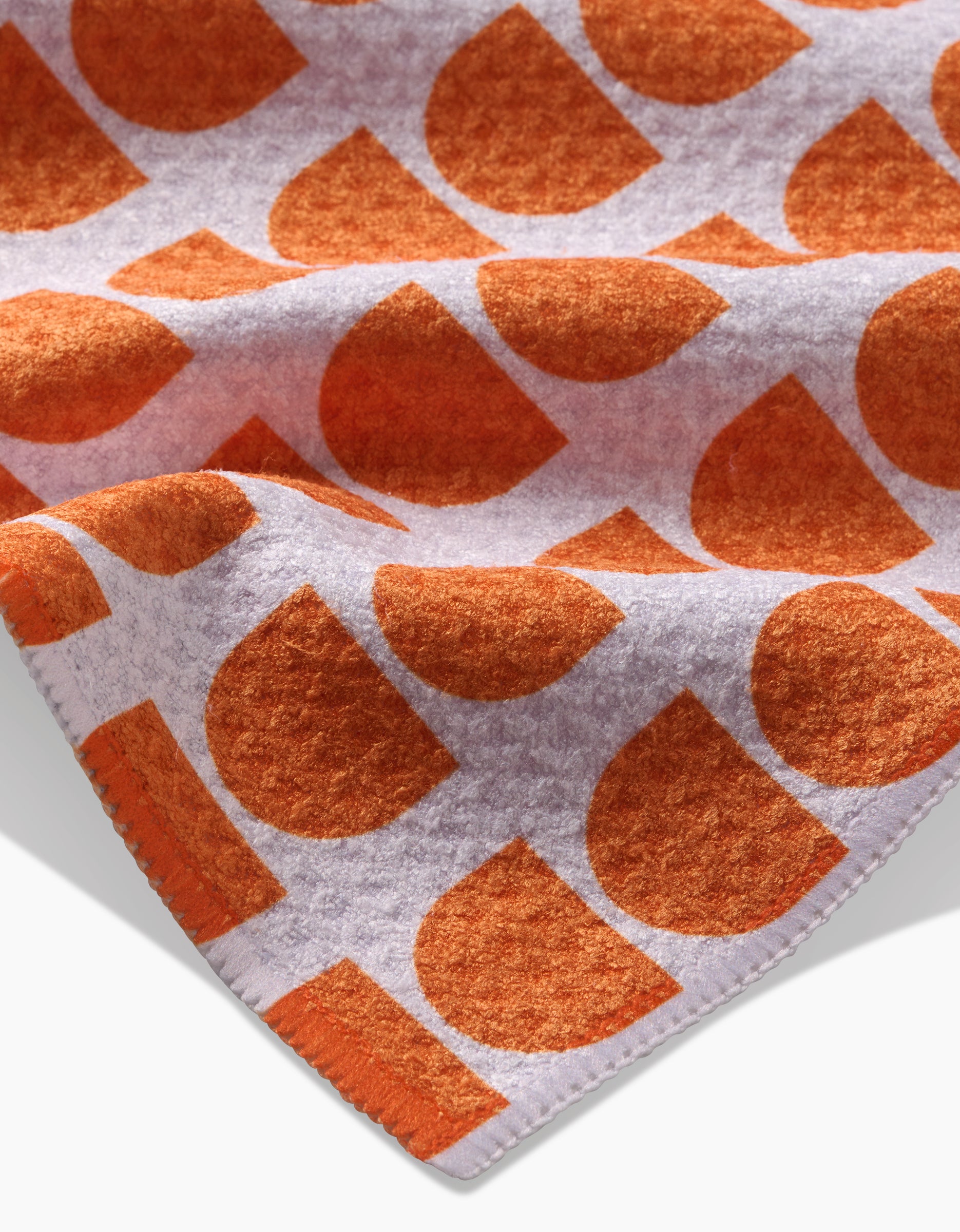 A close-up of Happy Hemera’s Pink Illusion, an ultra-absorbent Geoweave™ fabric made from recycled materials, featuring a textured surface and a bold orange and white geometric pattern of large semicircles and quarter circles.